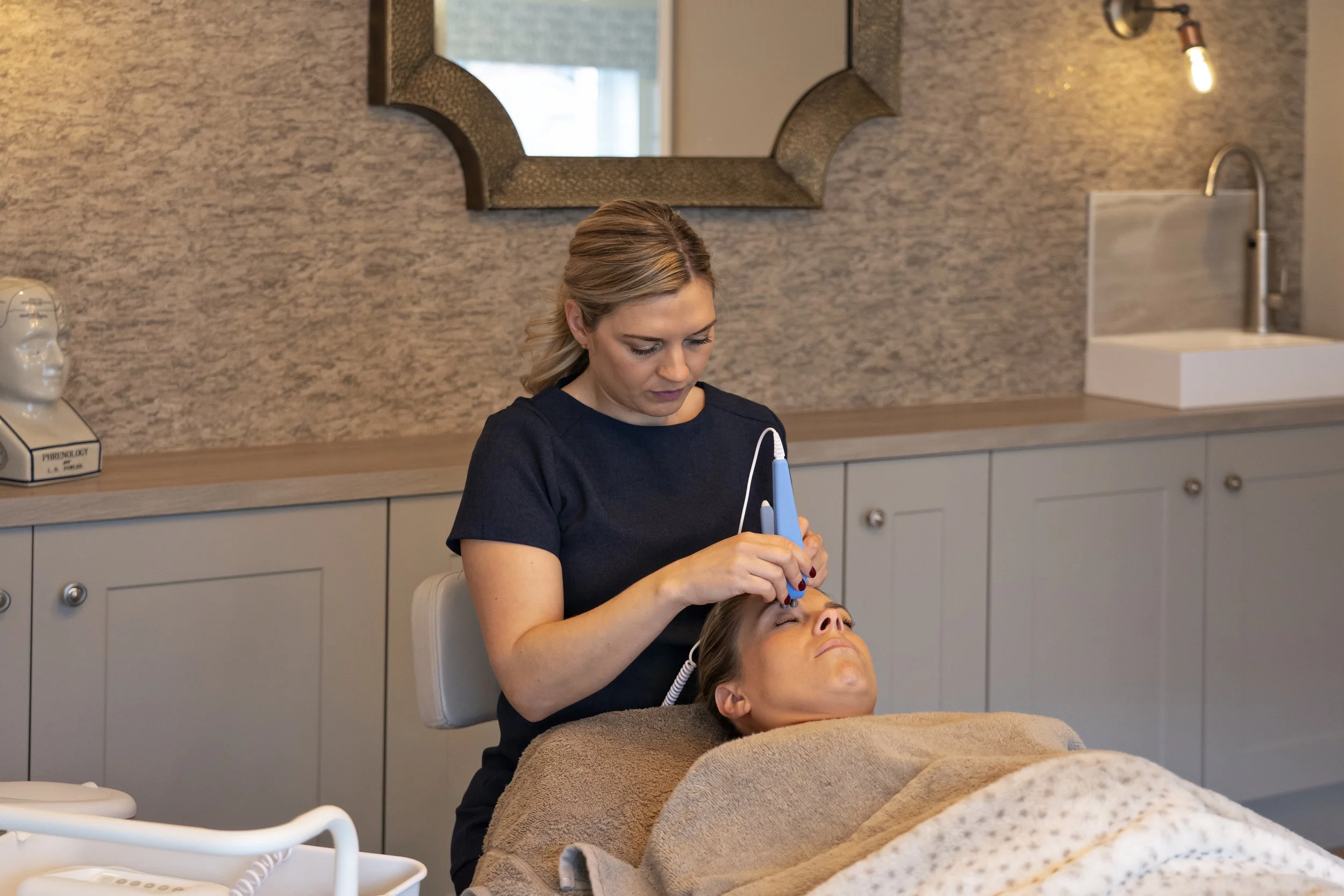 Jody Taylor performing a facial on a client at SkinDeep Clinic