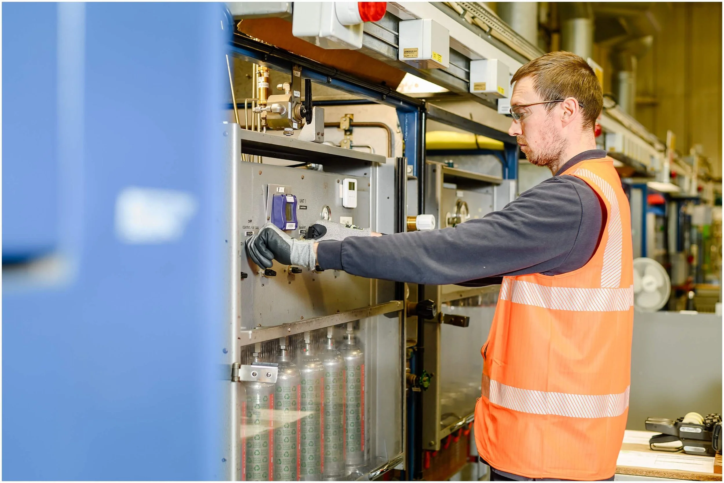 Worker in safety vest and gloves operating industrial machinery in a manufacturing facility