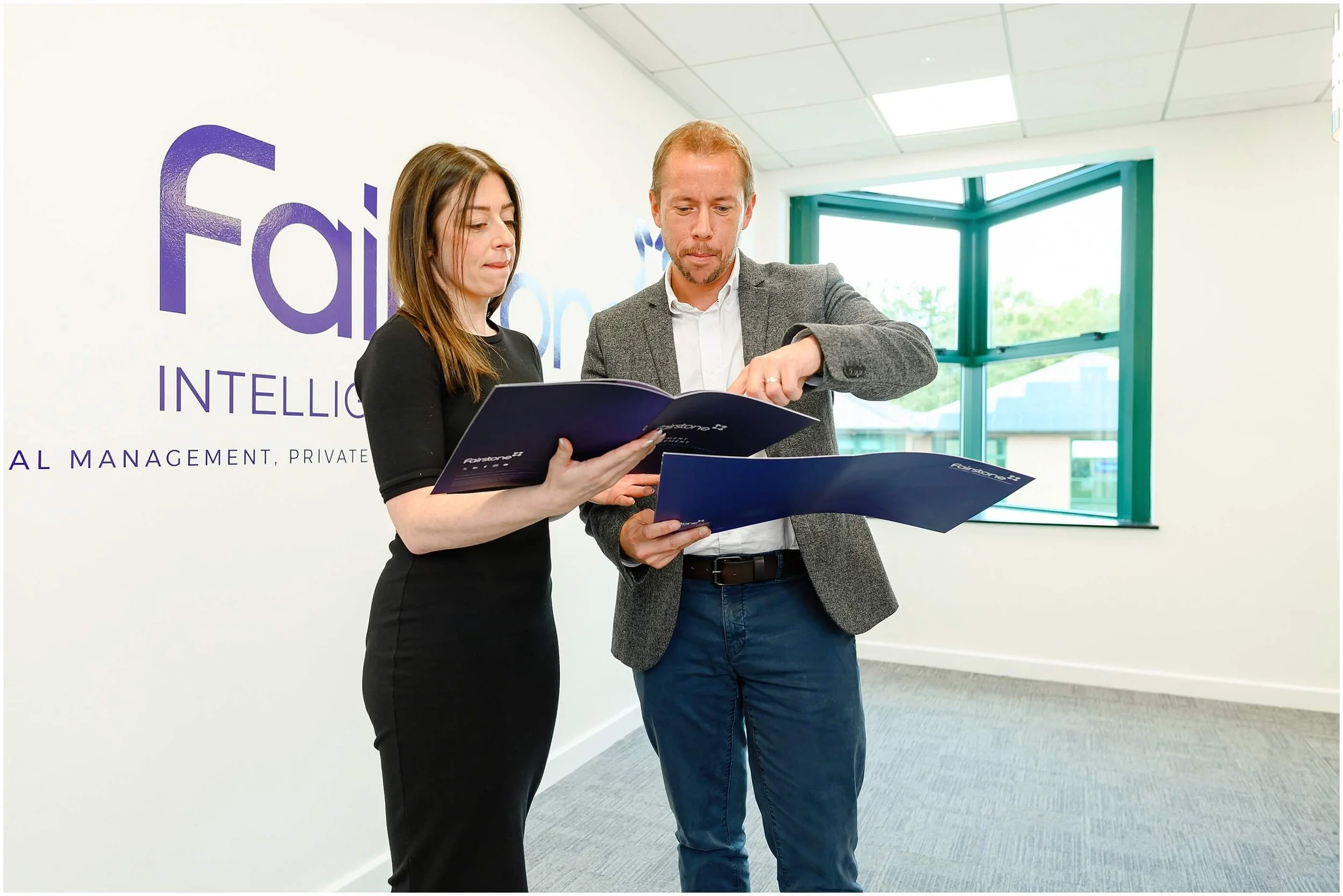 Two business professionals reviewing Fairstone brochures in a modern office.