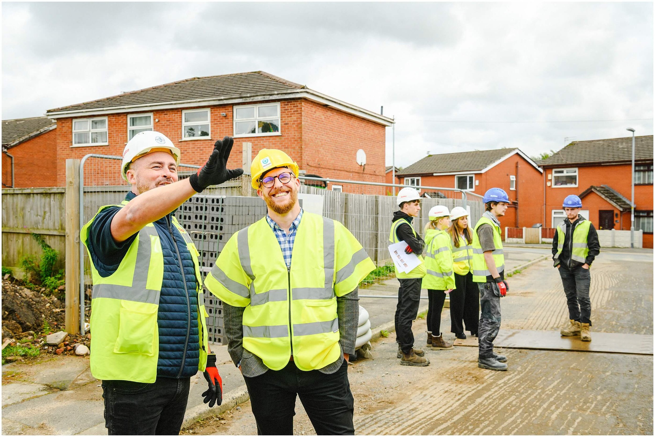 Construction workers in high-visibility vests and hard hats at a residential housing construction site