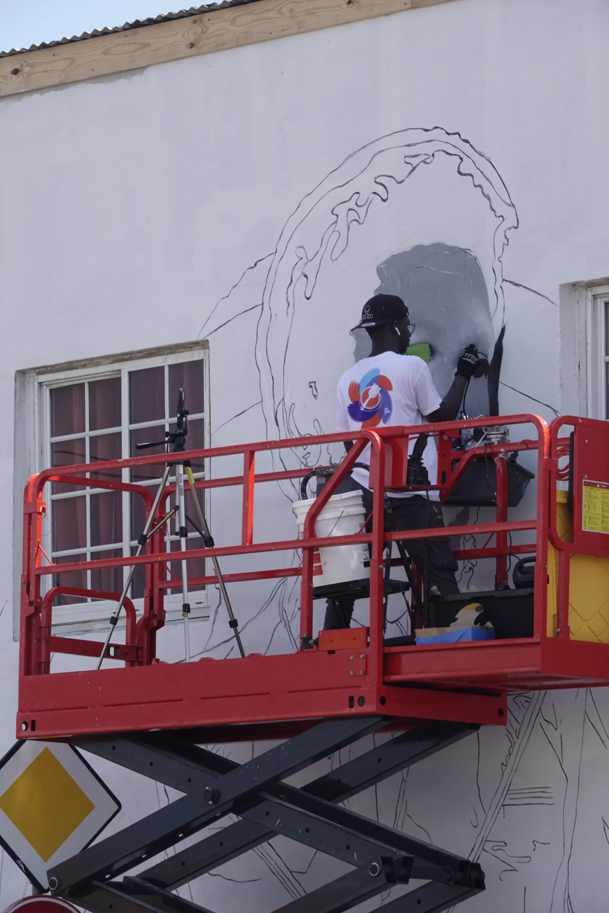 Artist painting large mural during Aruba and Curaçao street art project