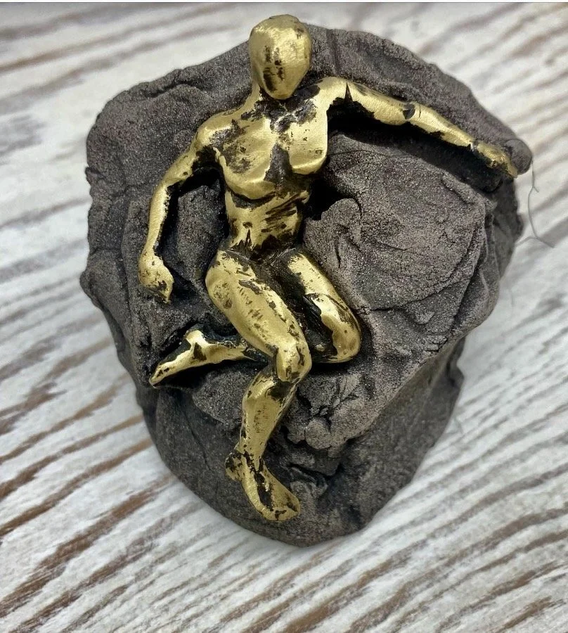 Abstract gold human sculpture embedded in stone, modern art decor