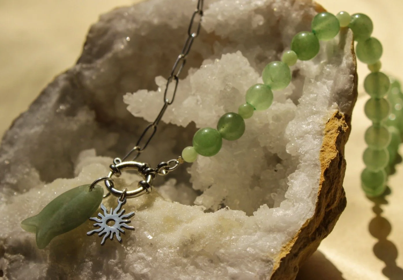Green jade beaded necklace with silver charm on natural crystal stone