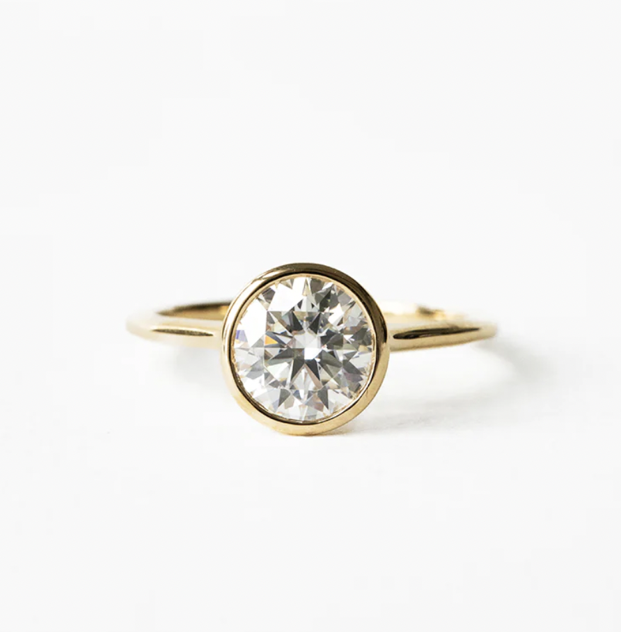 Close-up of a gold ring with a large round diamond solitaire setting on a white background.