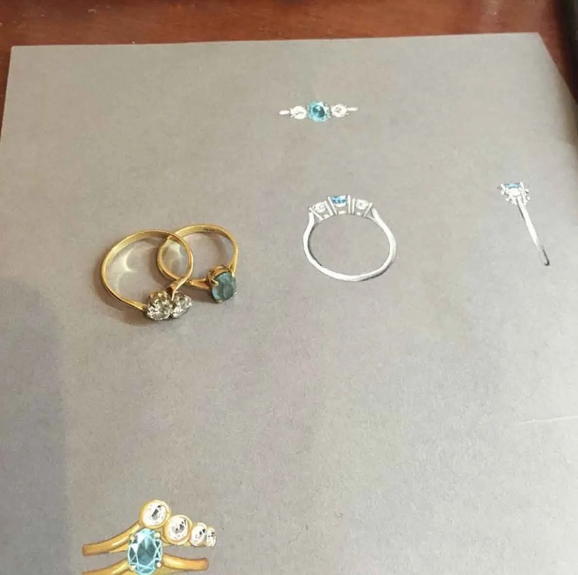 A collection of jewelry including gold and silver rings with gemstones, a ring with three stones, and a pair of gold earrings with a linked design, all arranged on a white surface.