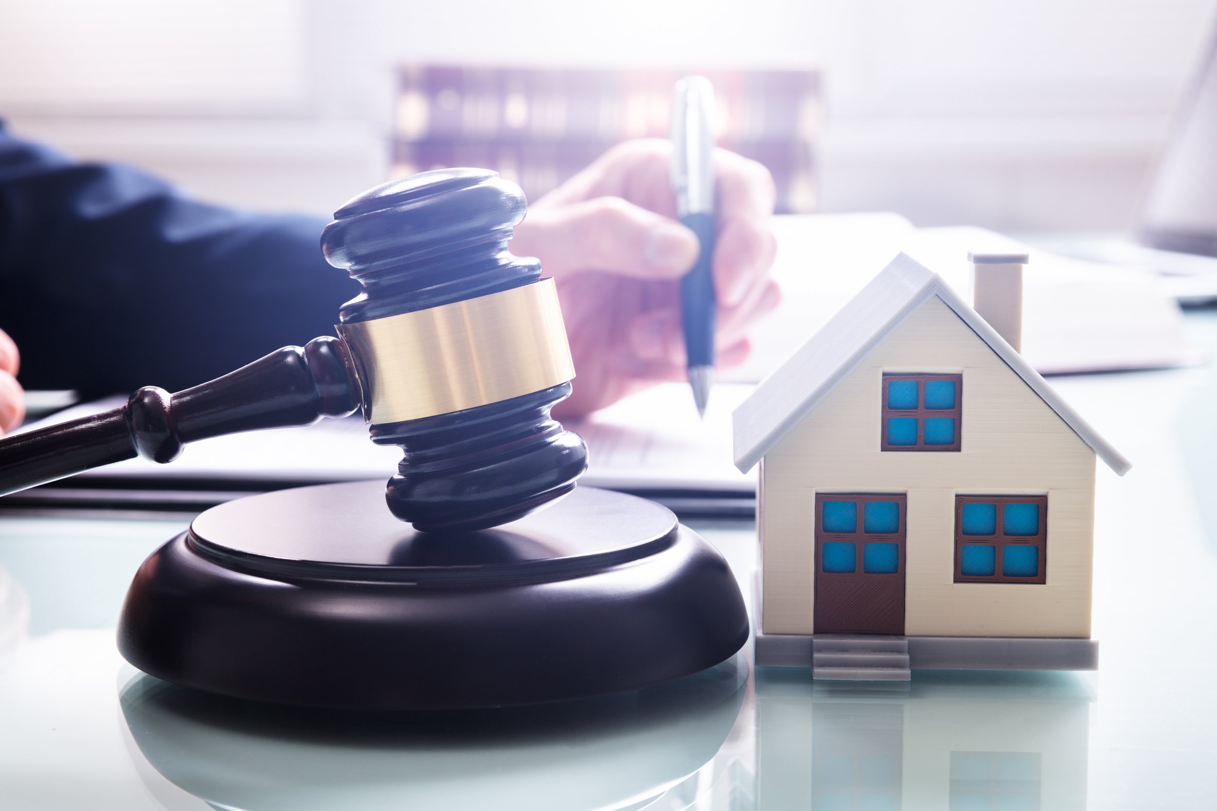 House-Model-With-Gavel-In-Front-Of-A-Businessperson-1141354654_3868x2579.jpeg