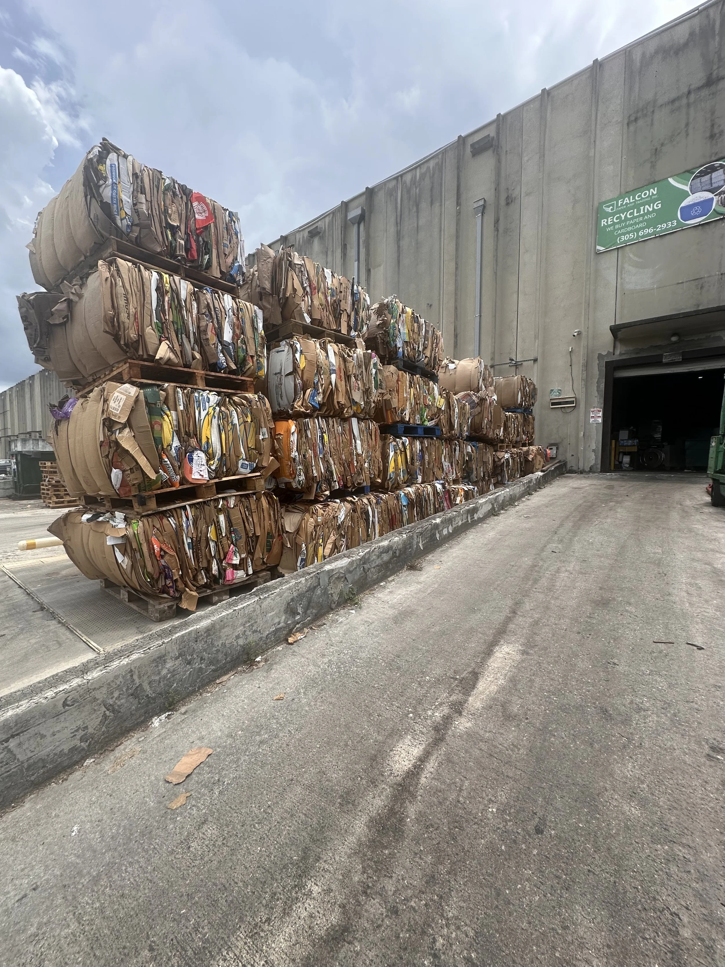 Stacked bales of compressed paper and cardboard outside Falcon Paper's warehouse.