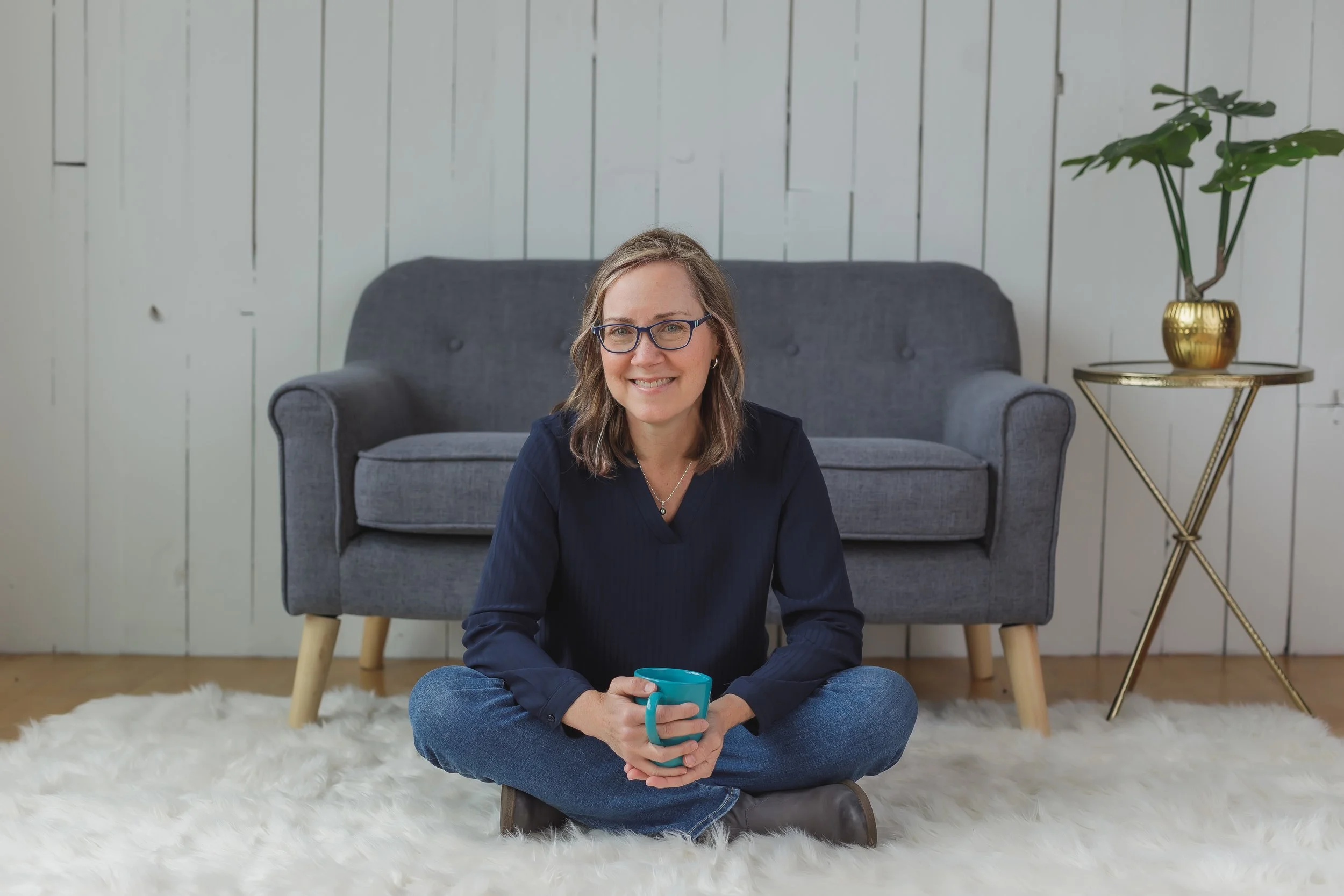 Parent and family therapist Kirsten Jensen sitting in front of a grey couch