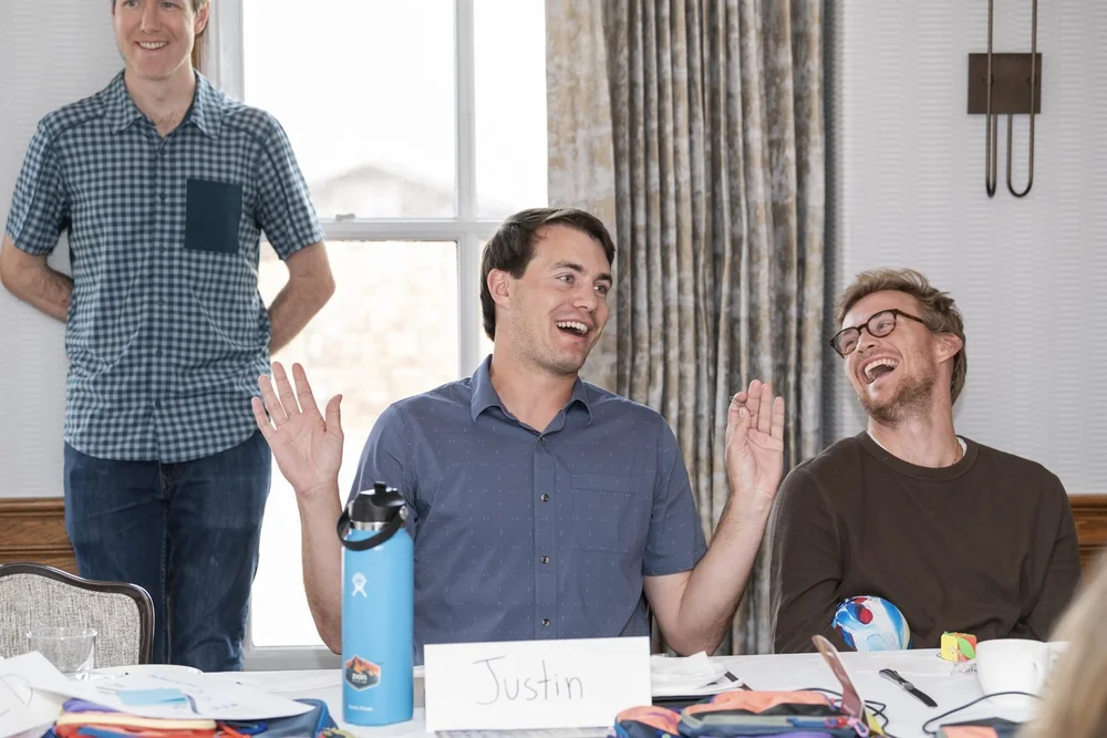 Excelerate teammates laughing together at a working-session table.