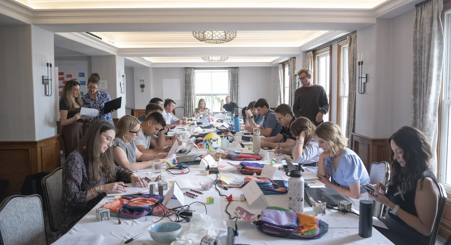 Excelerate consultants at work around a long table during a full-day working session.