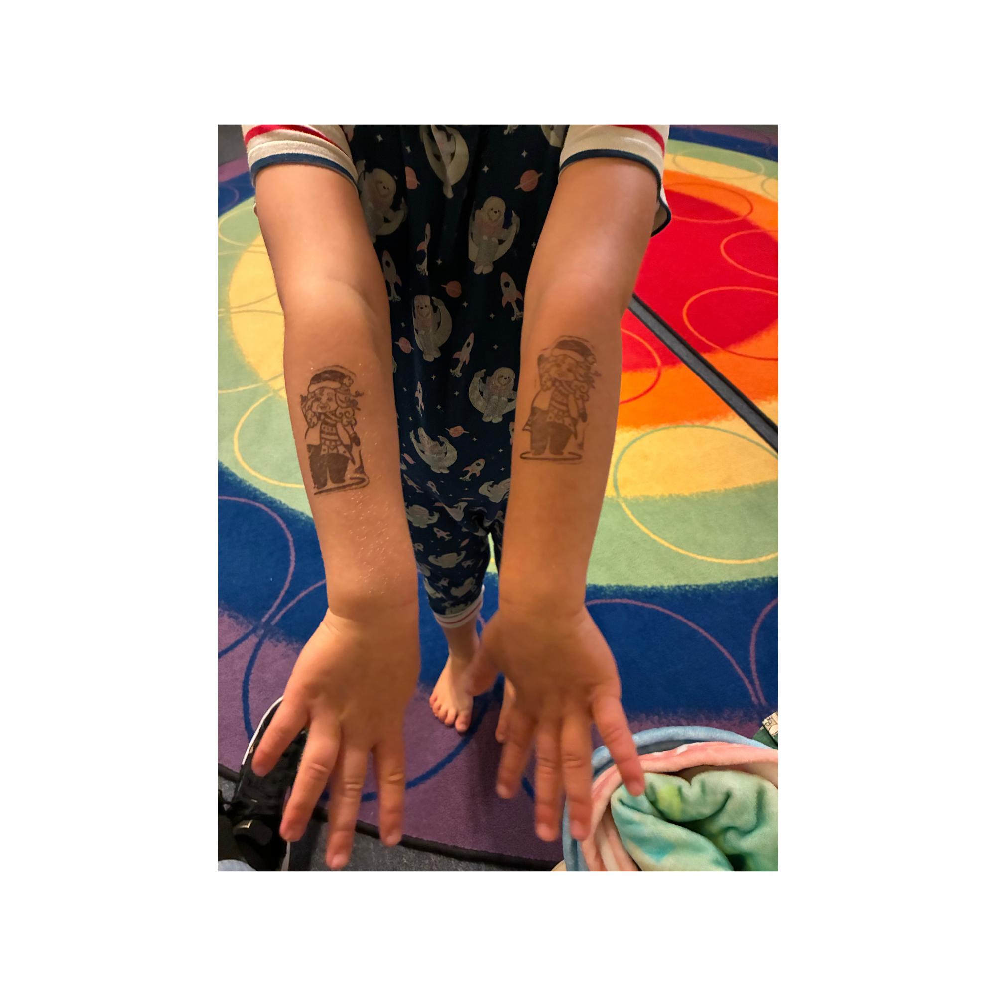 Arms of a young child, proudly displaying his stamp tattoo of Merry Claus
