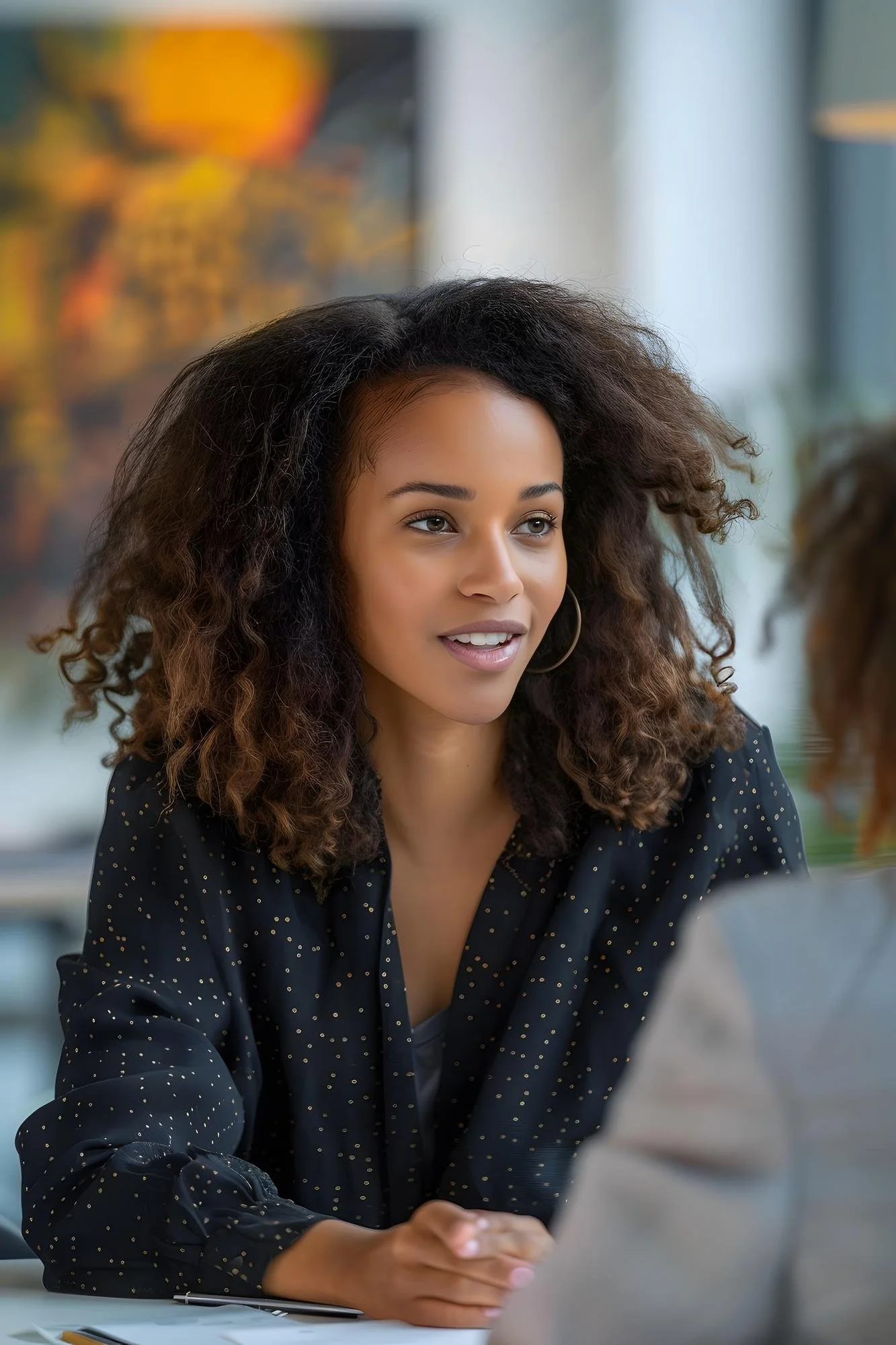 Young woman with curly hair engaged in conversation in an indoor setting.