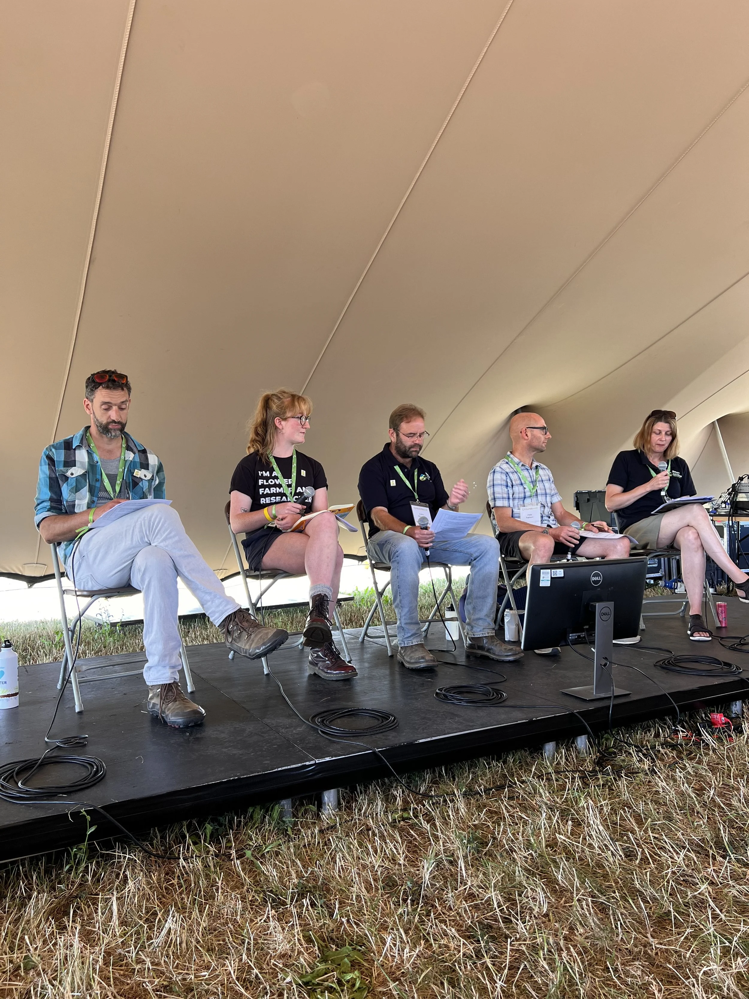 Roisin speaking on stage at Groundswell, she is sat on a panel with three other men and one woman, all farmers and scientists. 