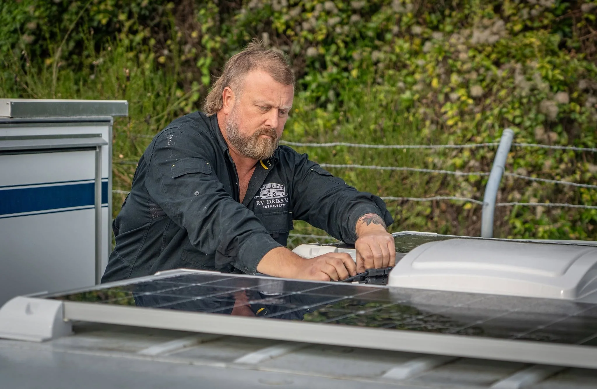 RV Dreams technician fitting a solar panel on a caravan roof in Upper Hutt