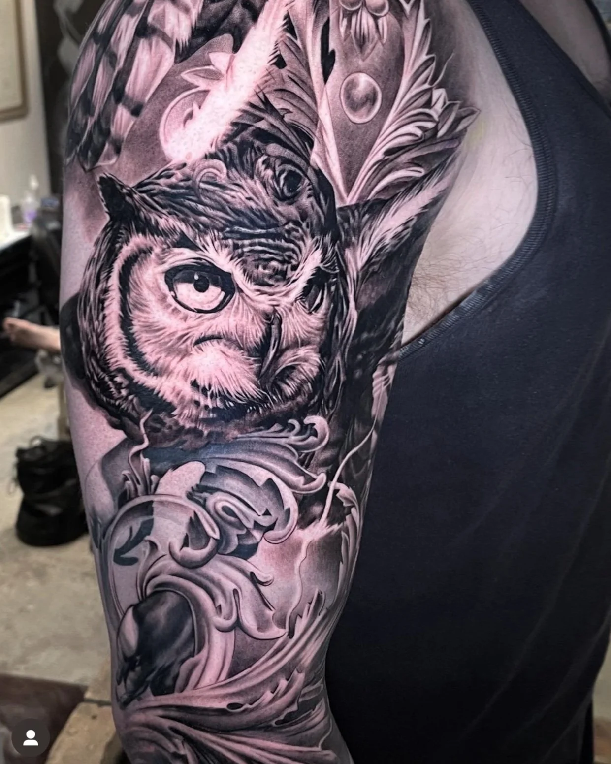 Black and gray tattoo of an owl with intricate linework on a person's upper arm and shoulder.