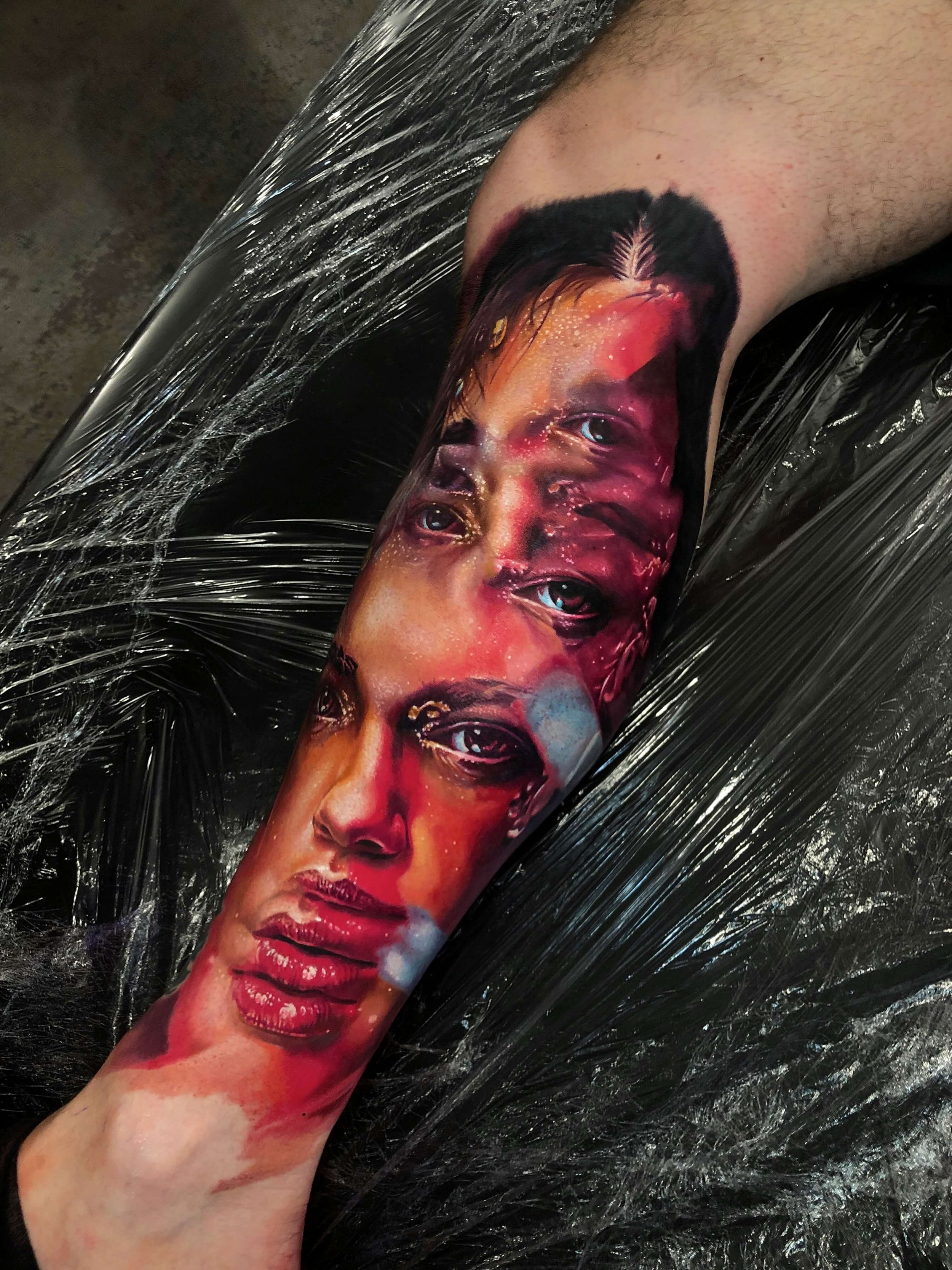 A tattoo of a woman's face with vivid, realistic details on a person's forearm.