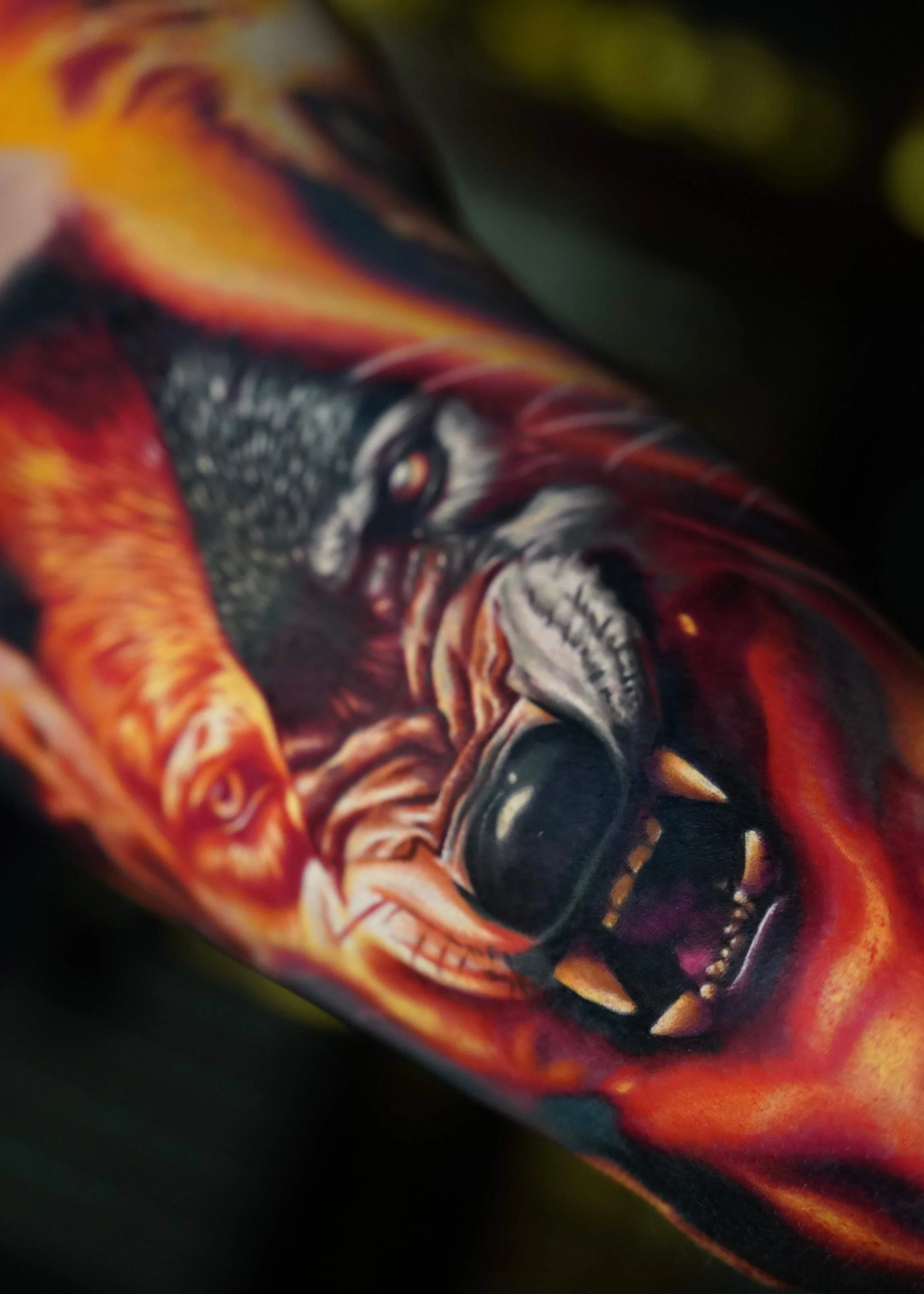 Close-up of a colorful, abstract dragon design on fabric or artwork, featuring fiery reds, oranges, yellow, and dark shades with intricate details.
