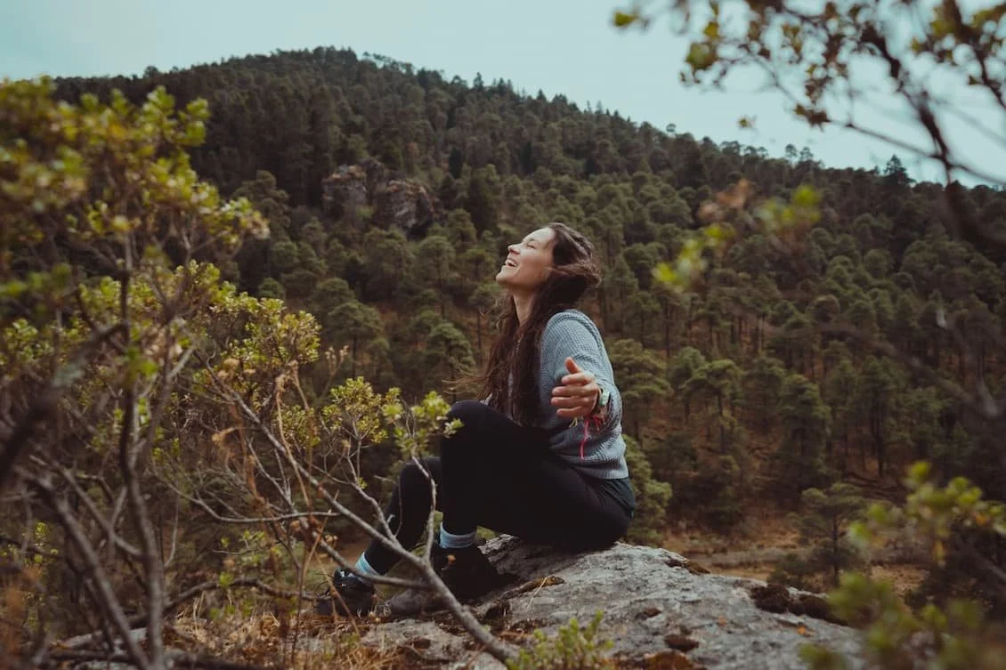happy-woman-sitting-in-a-boulder