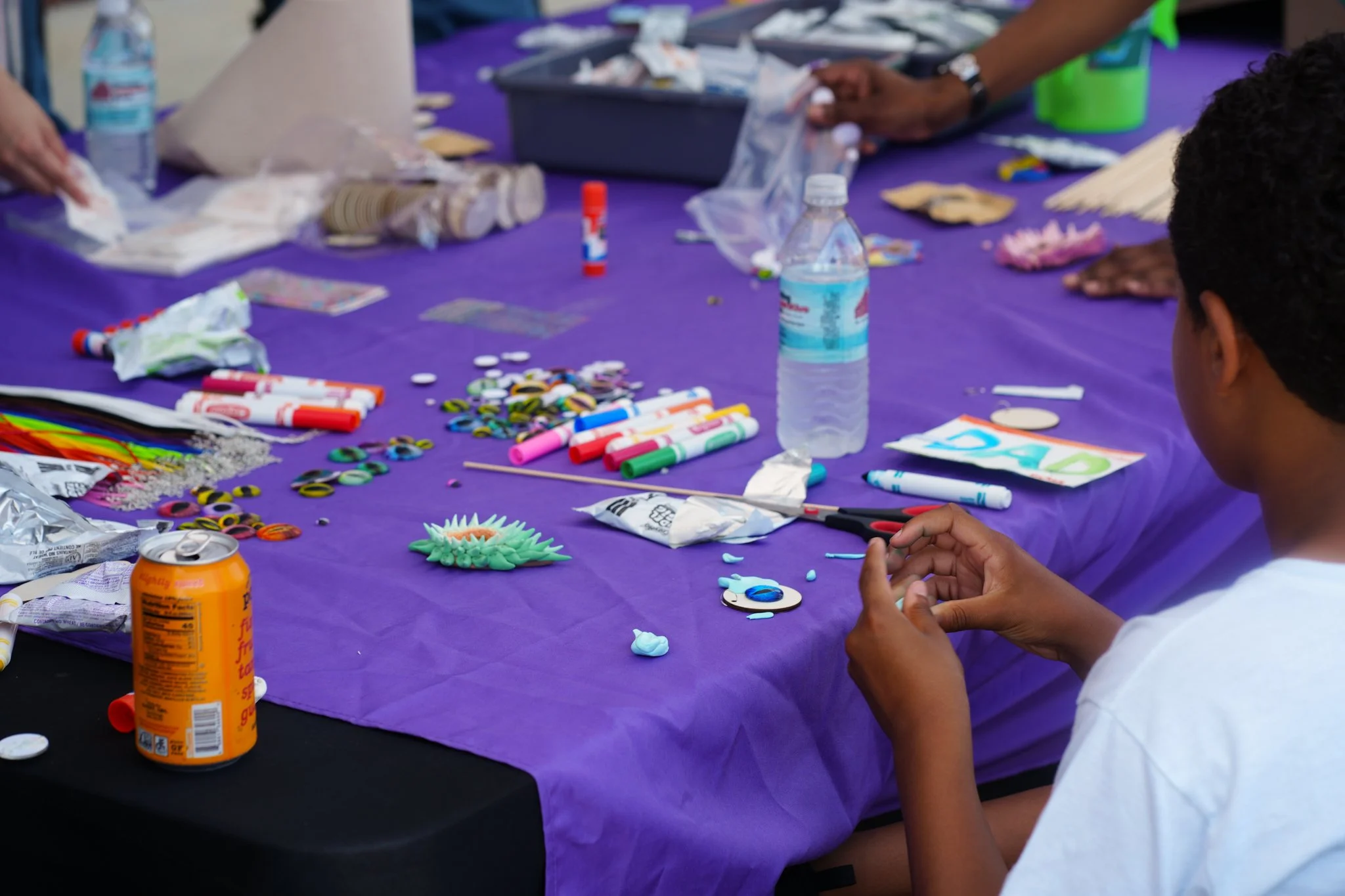 Child sitting at a table with colorful art supplies, decorated cookies, and a