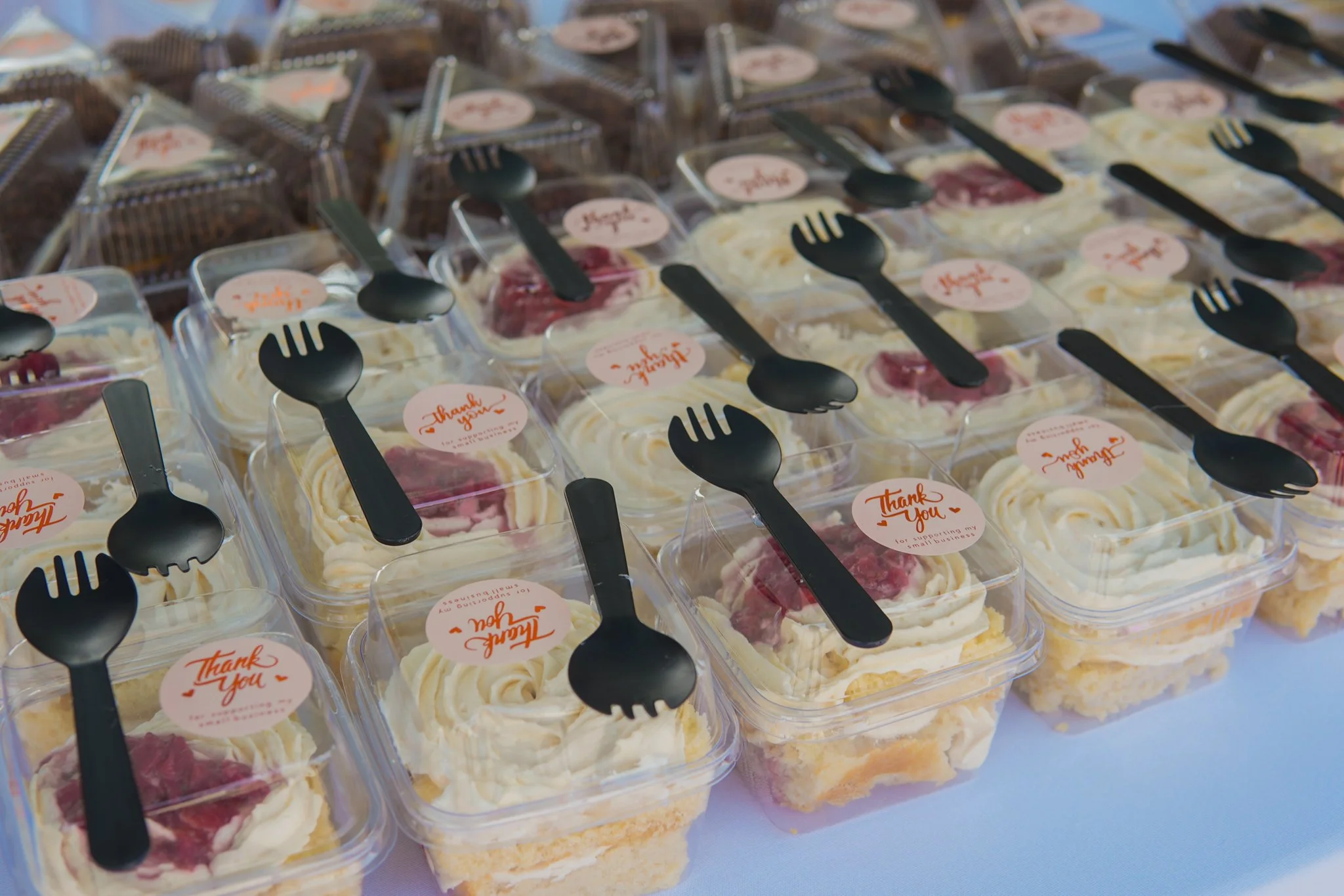 Small dessert cups with whipped cream and berry topping, each with a black plastic fork and a 'Thank You' sticker.