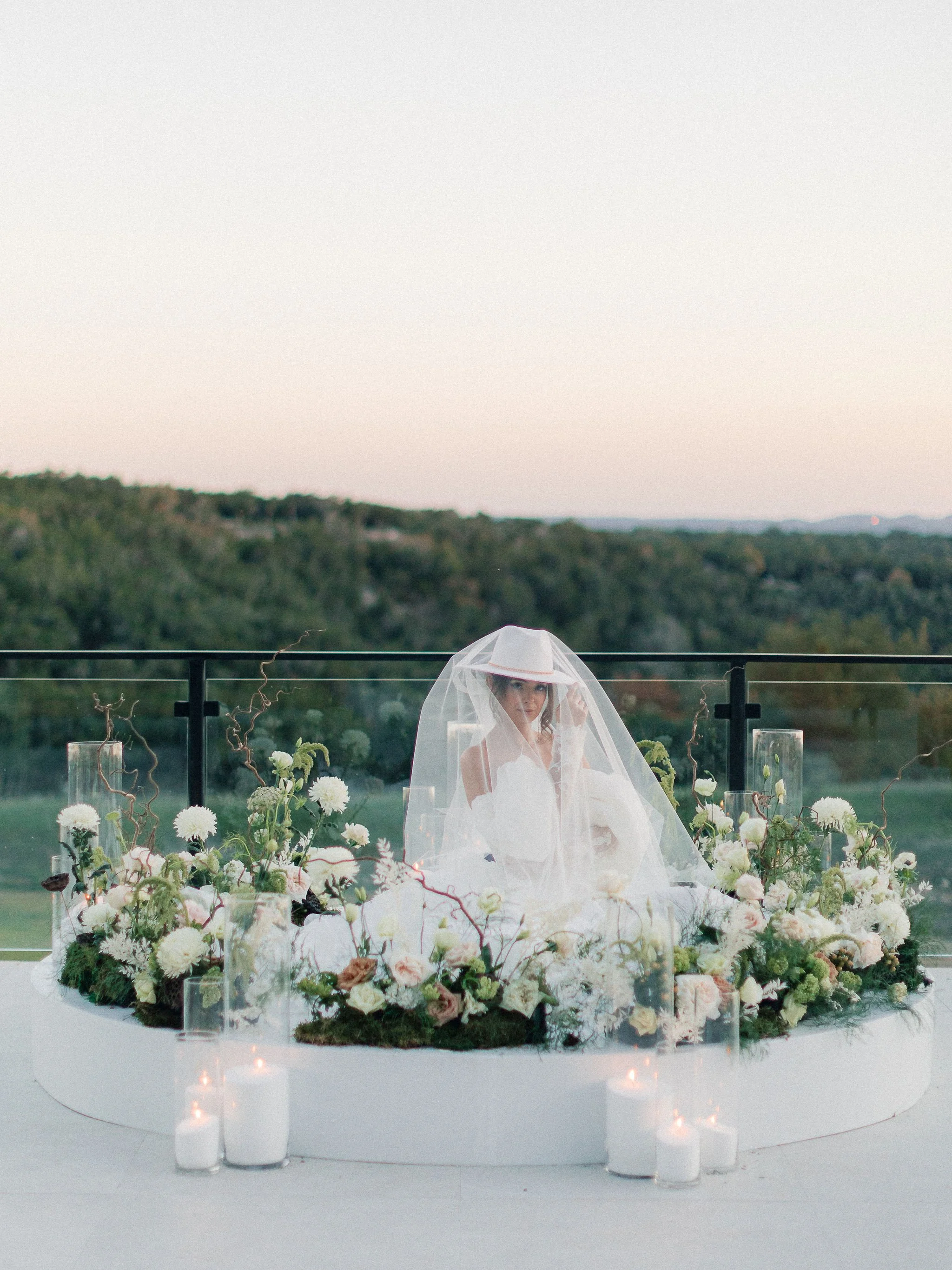 Bride at ceremony alter with floral arrangements overlooking the Texas Hill Country at The Videre Estate wedding venue.
