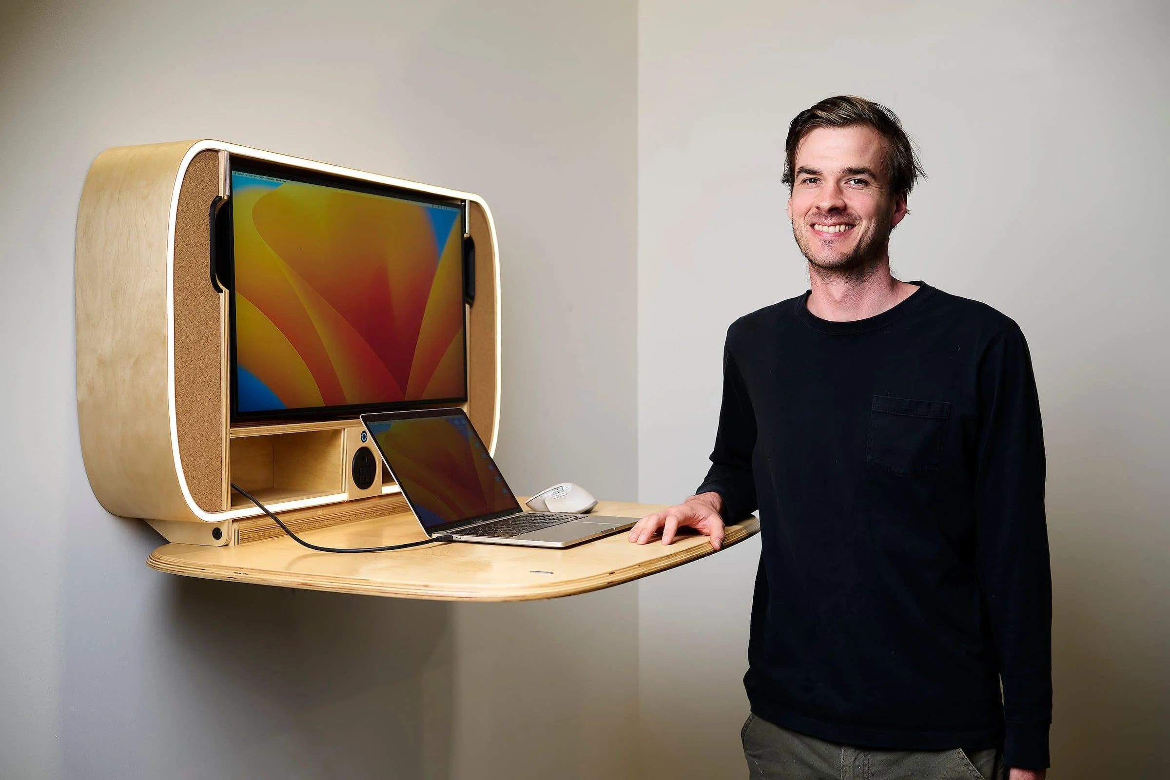 Man poses by murphy desk with laptop and built in monitor