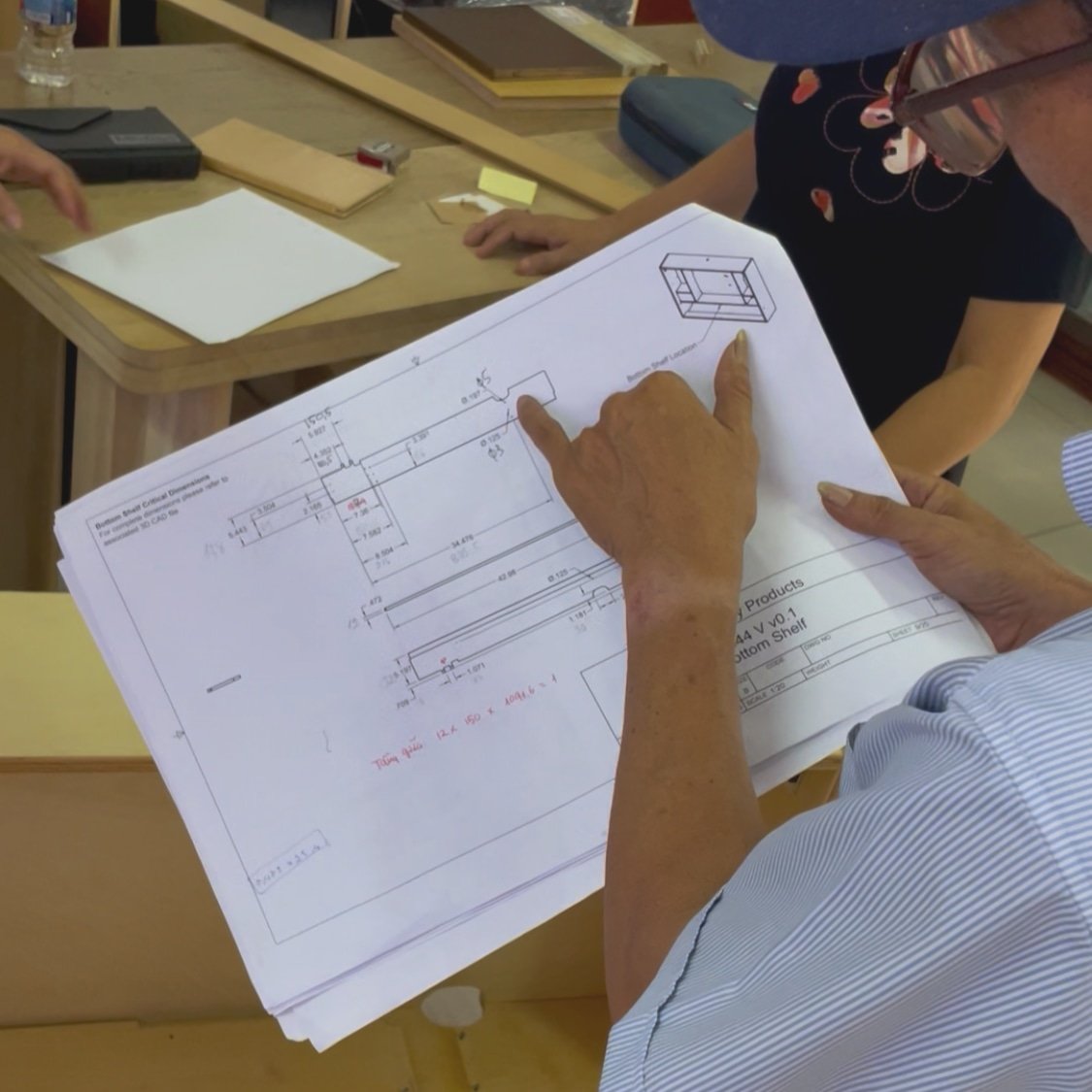 Man inspects engineering drawings of Razorclam Murphy Desk