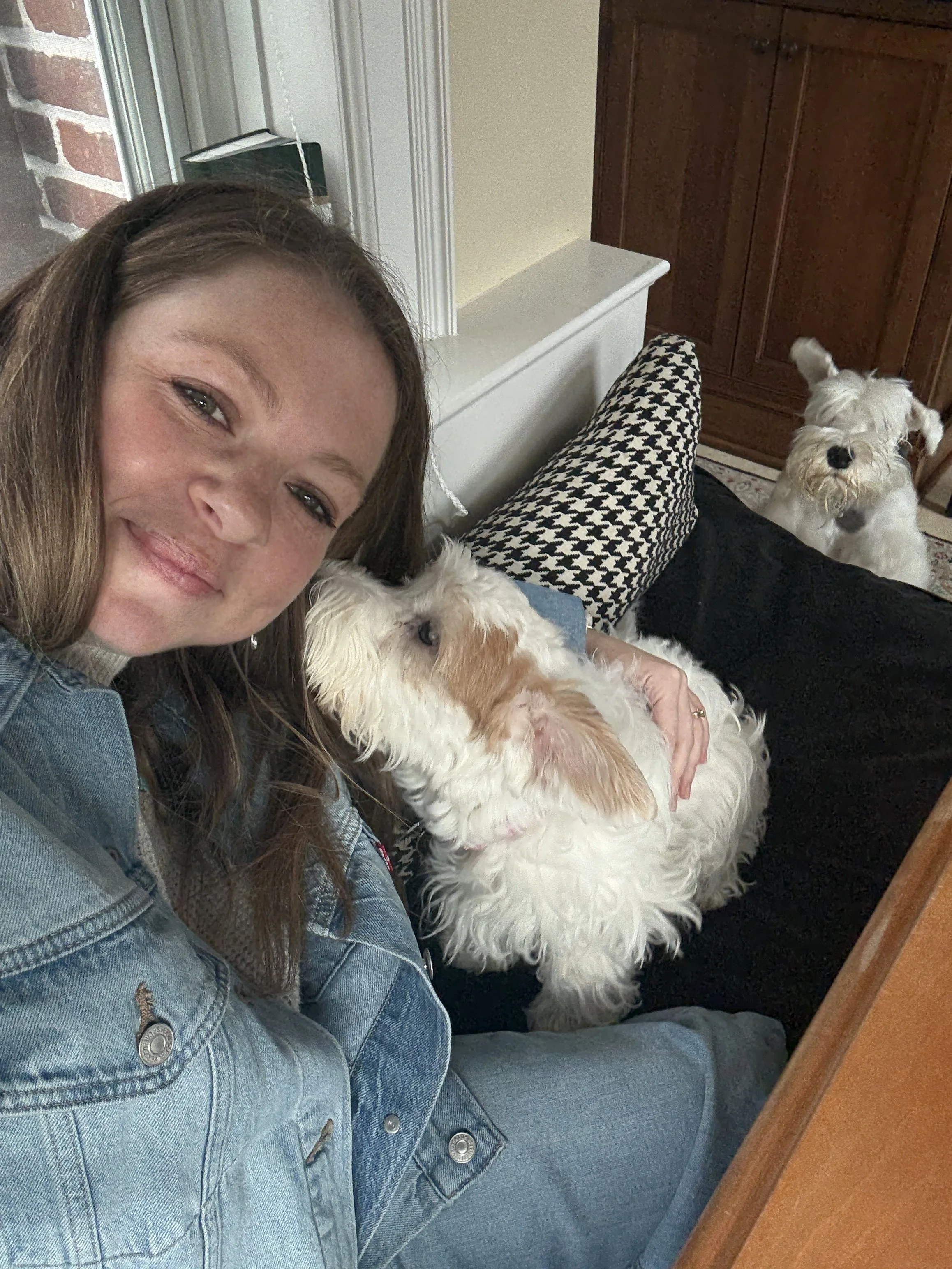 Girl smiling at camera with dog kissing her.