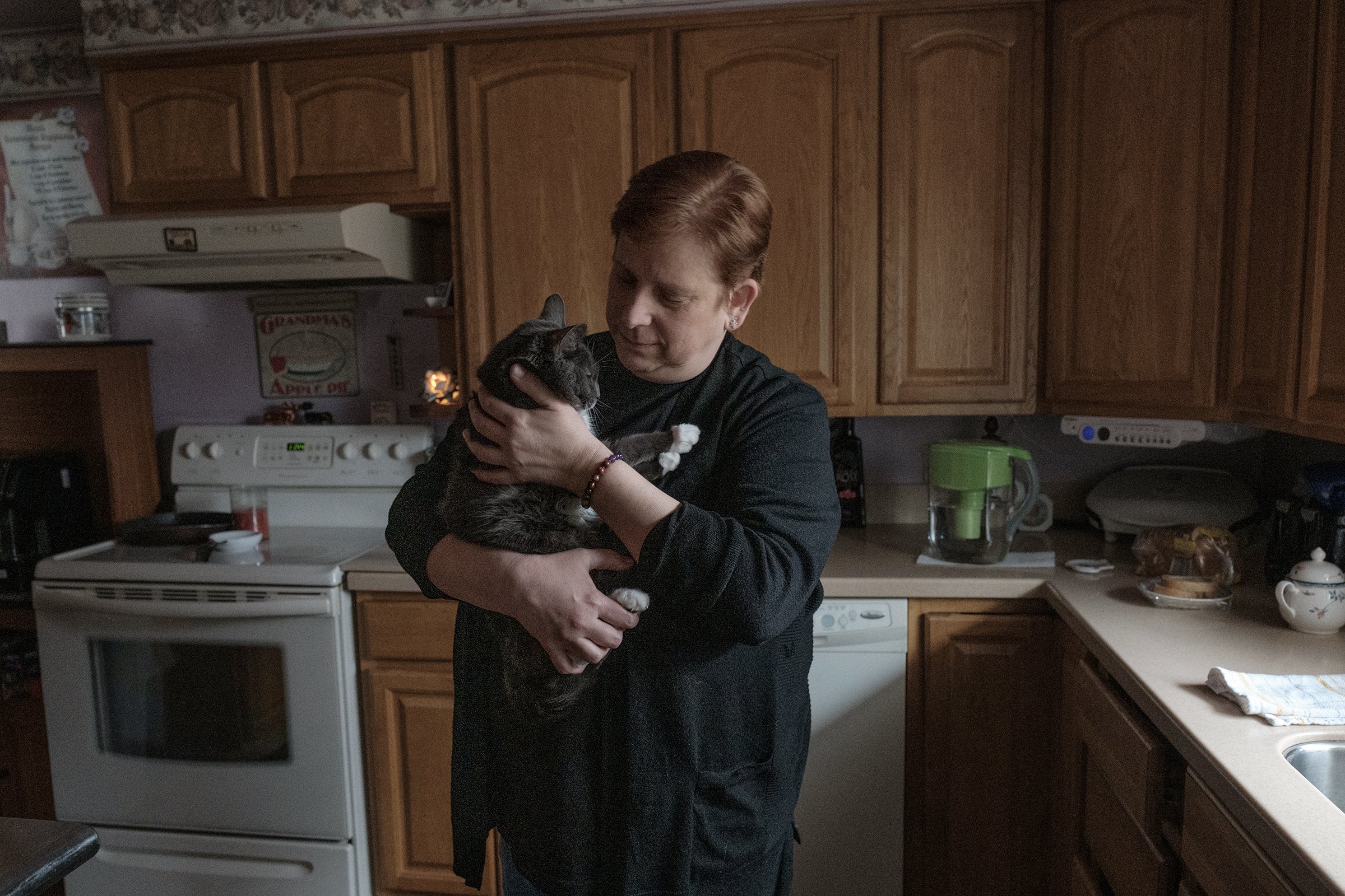 Renee Funkhouser with her cat, Ashes, in the kitchen of her East Palestine home on Jan. 31, 2024. Renee, her mother, Mary Lou Sovich, and Ashes spent six months living in a pet-friendly hotel in North Lima, Ohio, while cleanup efforts took place.