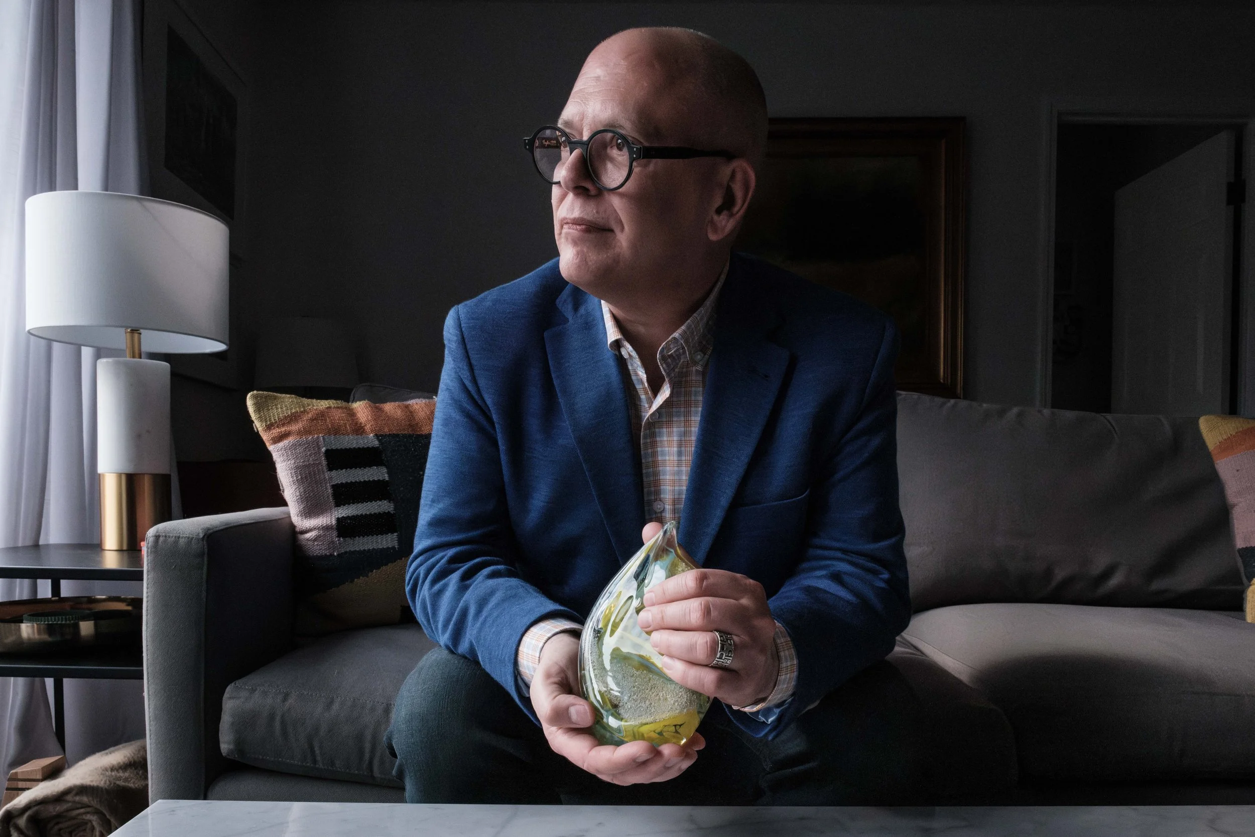 Jim Obergefell at his home in Sandusky, Ohio, holding a glass sculpture and wearing fused wedding rings — both of which contain the ashes of his late husband, John Arthur.