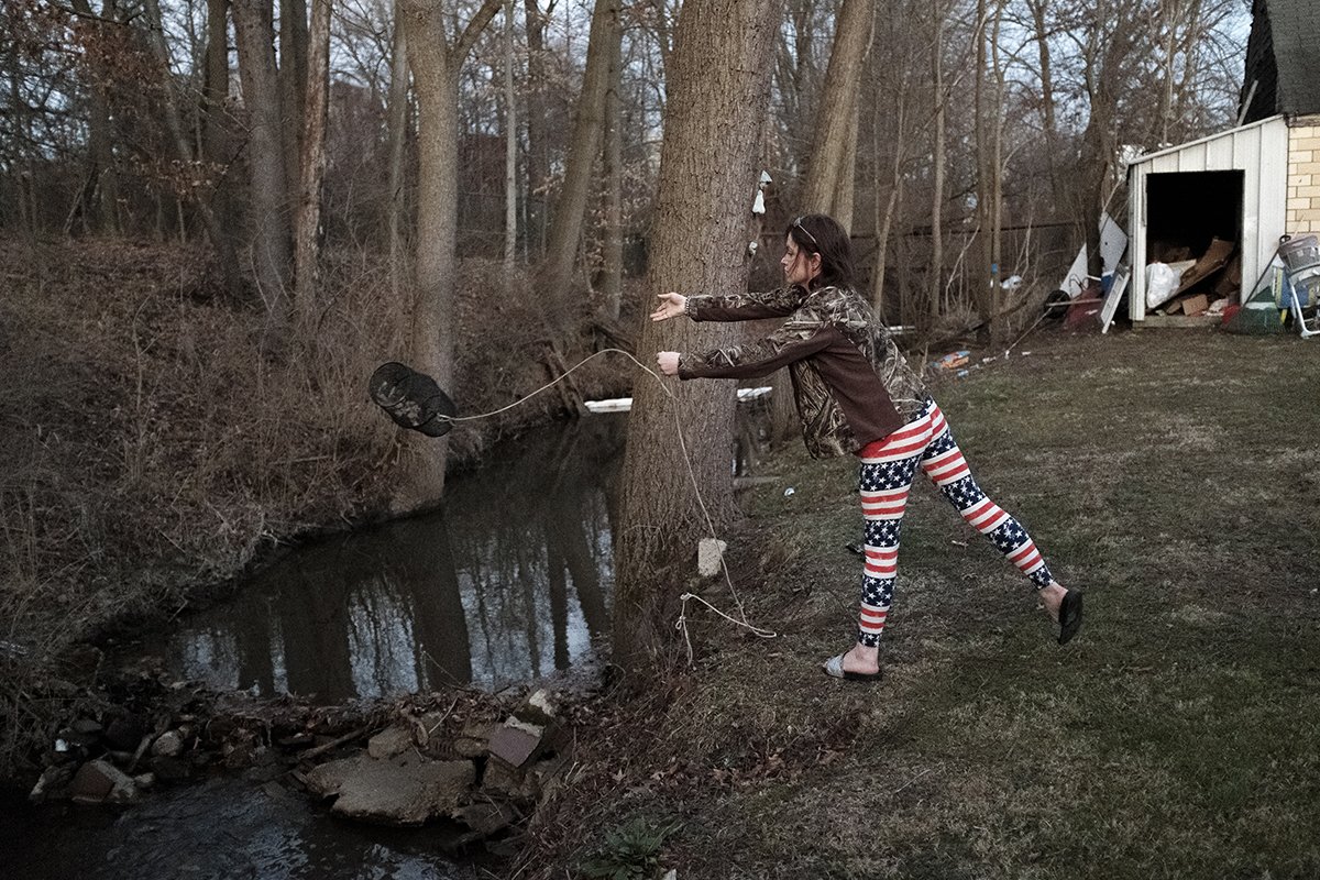 Courtney Miller tosses a minnow trap into Sulphur Run, the heavily contaminated creek that runs behind her house. She caught no living fish.