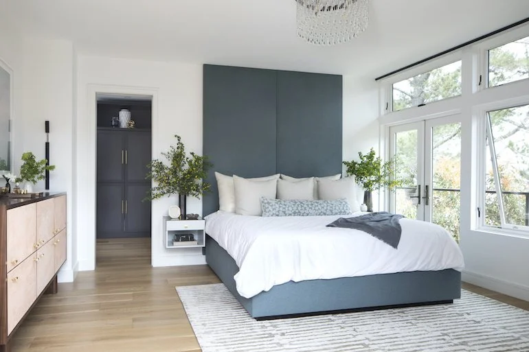 Stylish bedroom with a blue headboard and a white bed, reflecting the design expertise of Julie Rootes Interiors.