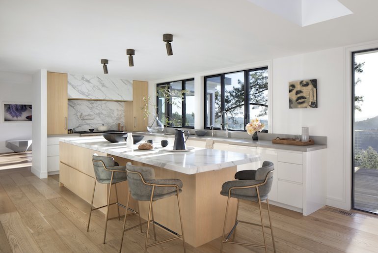 Modern kitchen showcasing a marble island and warm wooden floors, created by Julie Rootes Interiors.