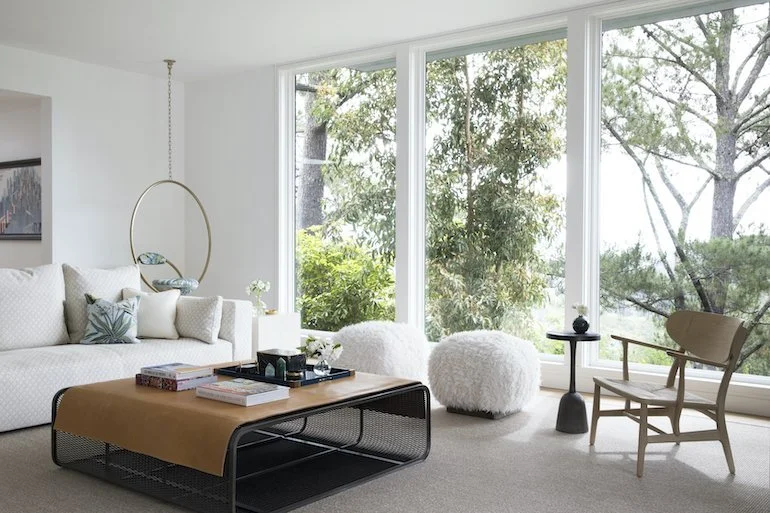 Elegant living room with white furnishings and large windows, showcasing the design expertise of Julie Rootes Interiors.