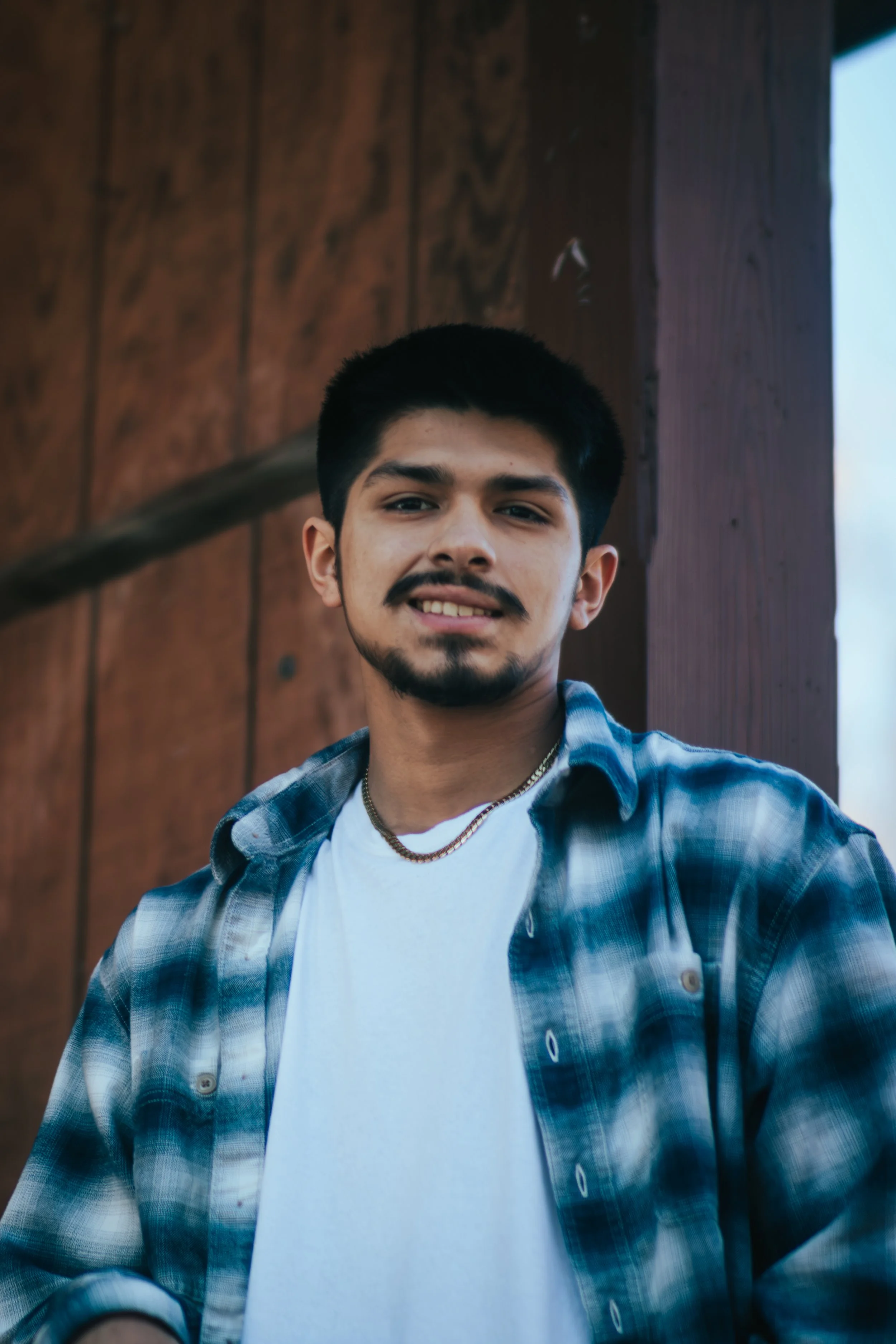 Alternate senior portrait of the same Bad River young man outdoors, wearing a plaid shirt, captured during his senior photo session.