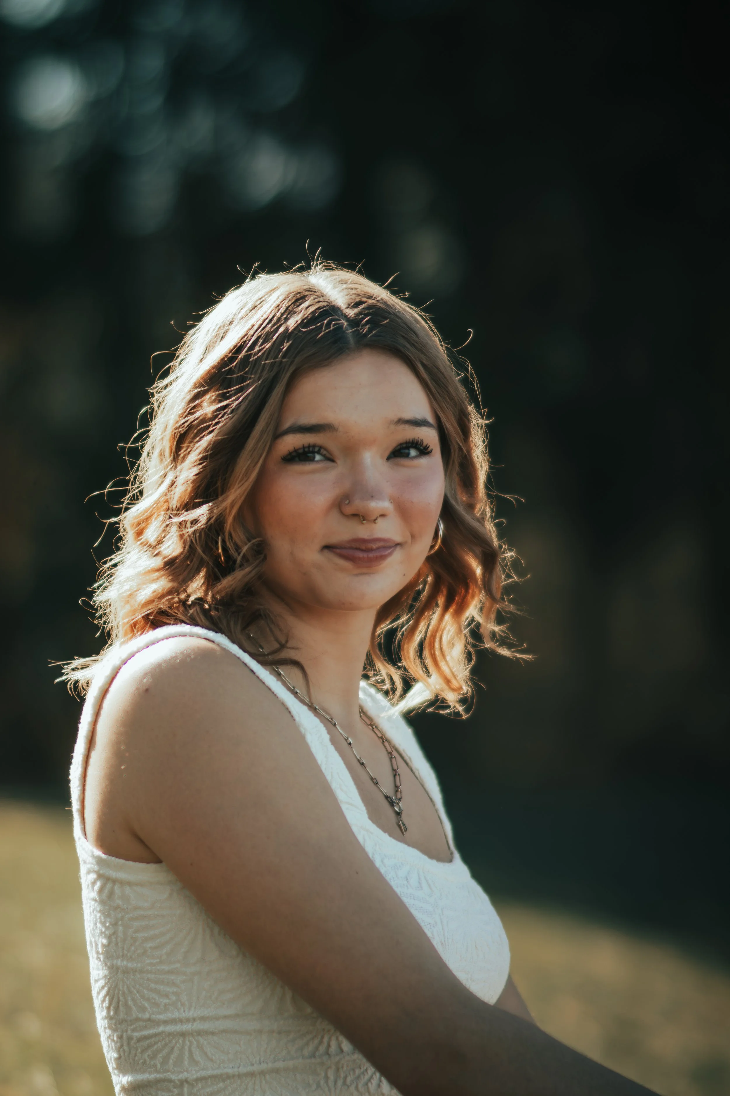 Senior portrait of a Red Cliff Nation young woman, smiling outdoors in natural light during her senior photo session.