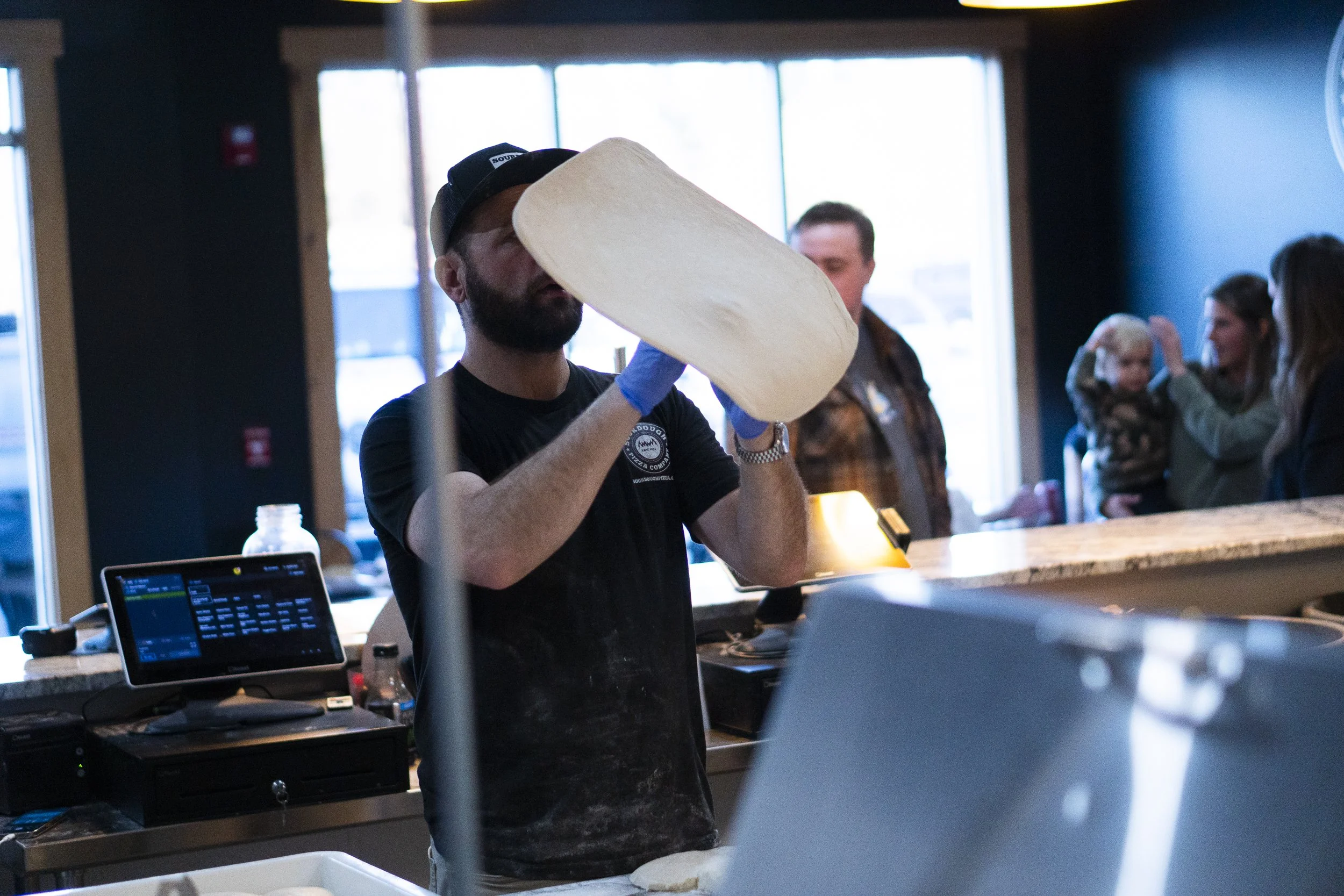 a sourdough pizza employee tosses a fresh sourdough pizza dough