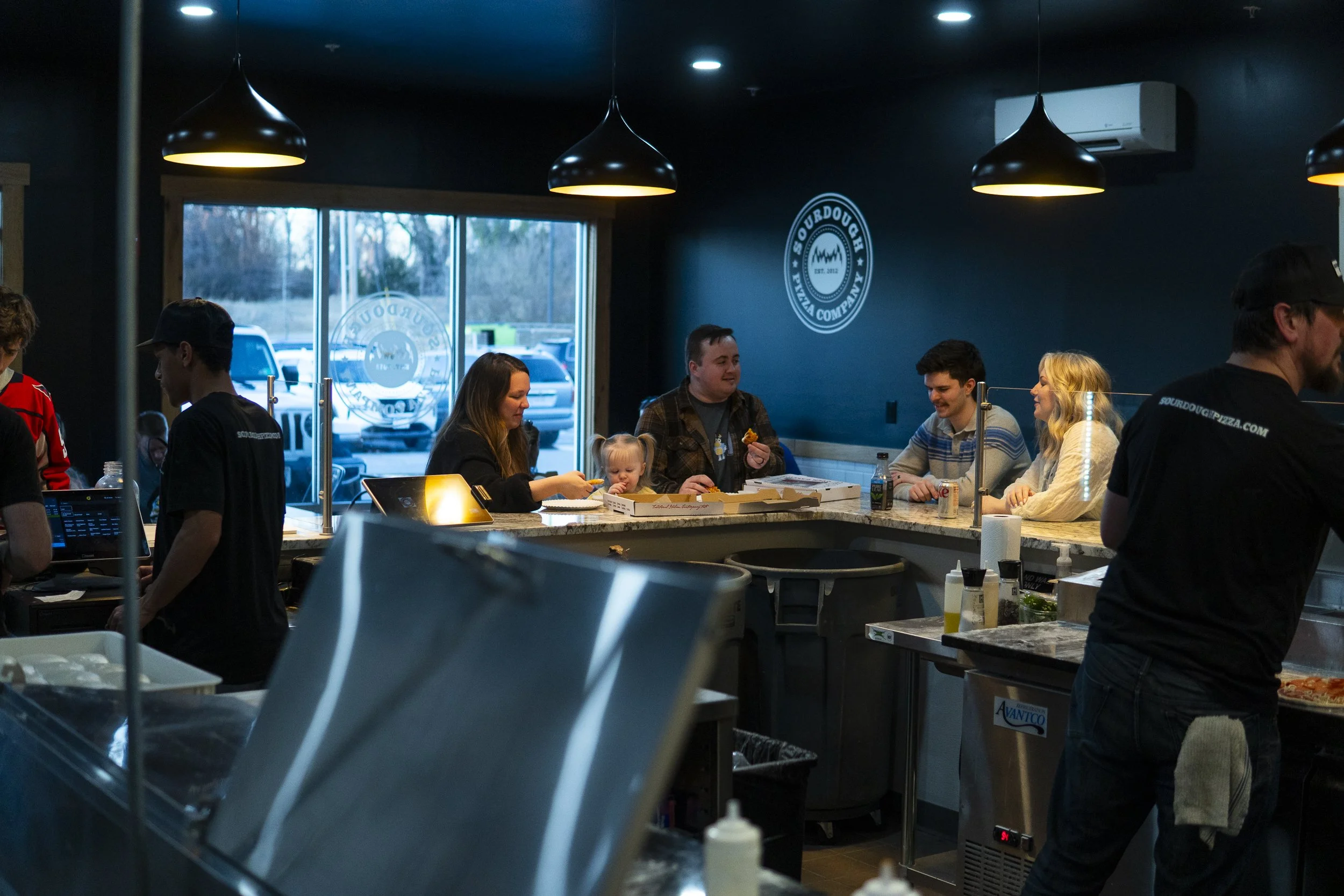 a group of customers sitting inside the sourdough pizza company pizzeria enjoying their pizza