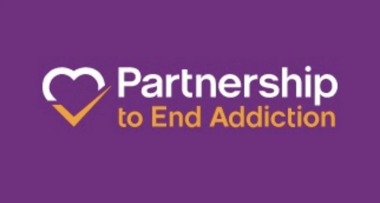 Logo for Partnership to End Addiction with a purple background, a white and purple heart with an orange checkmark, and the text 'Partnership to End Addiction' in white and orange.