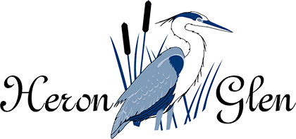 Illustration of a heron standing among marsh reeds with the words "Heron Glen" in elegant script.