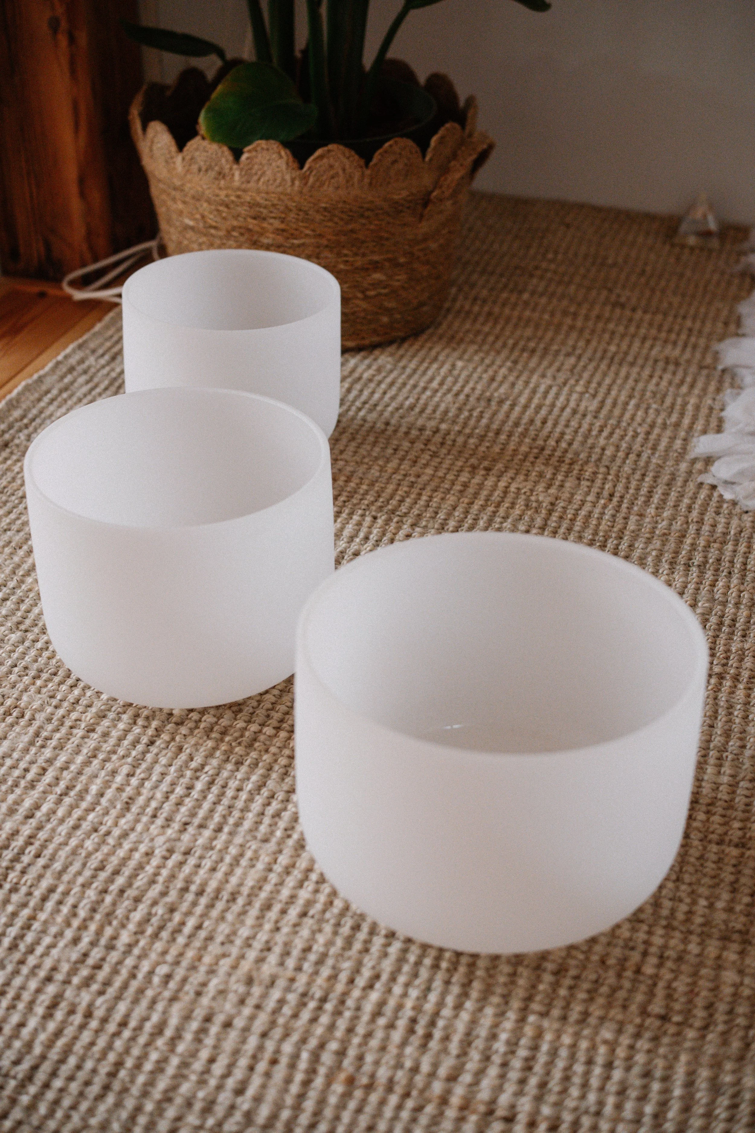 Three white crystal bowls on a rug.