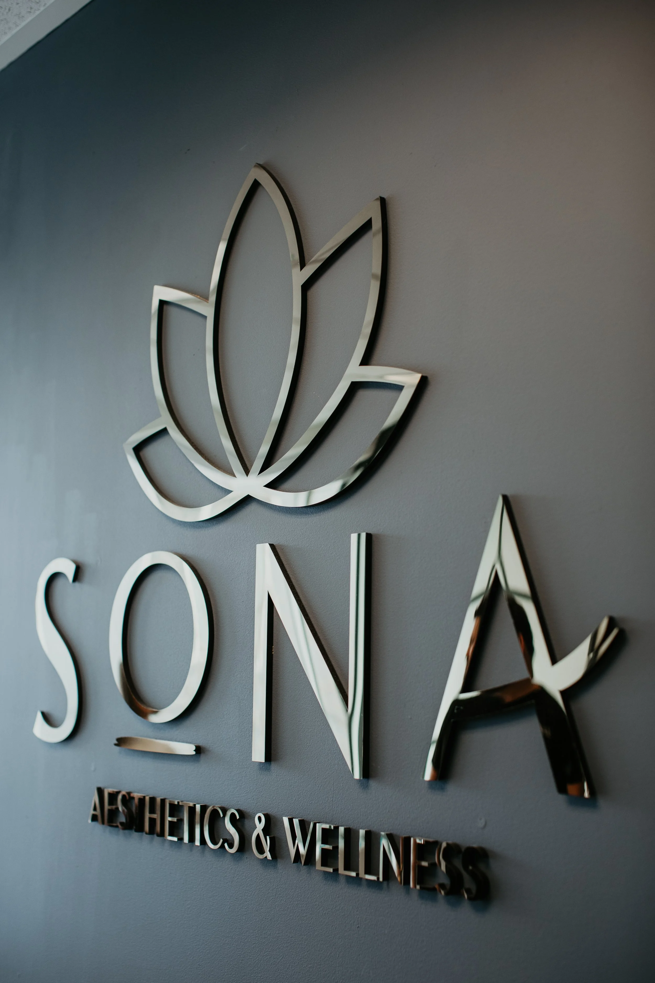 Sona Aesthetics and Wellness metal wall sign with lotus logo at boutique med spa in Newcastle WA