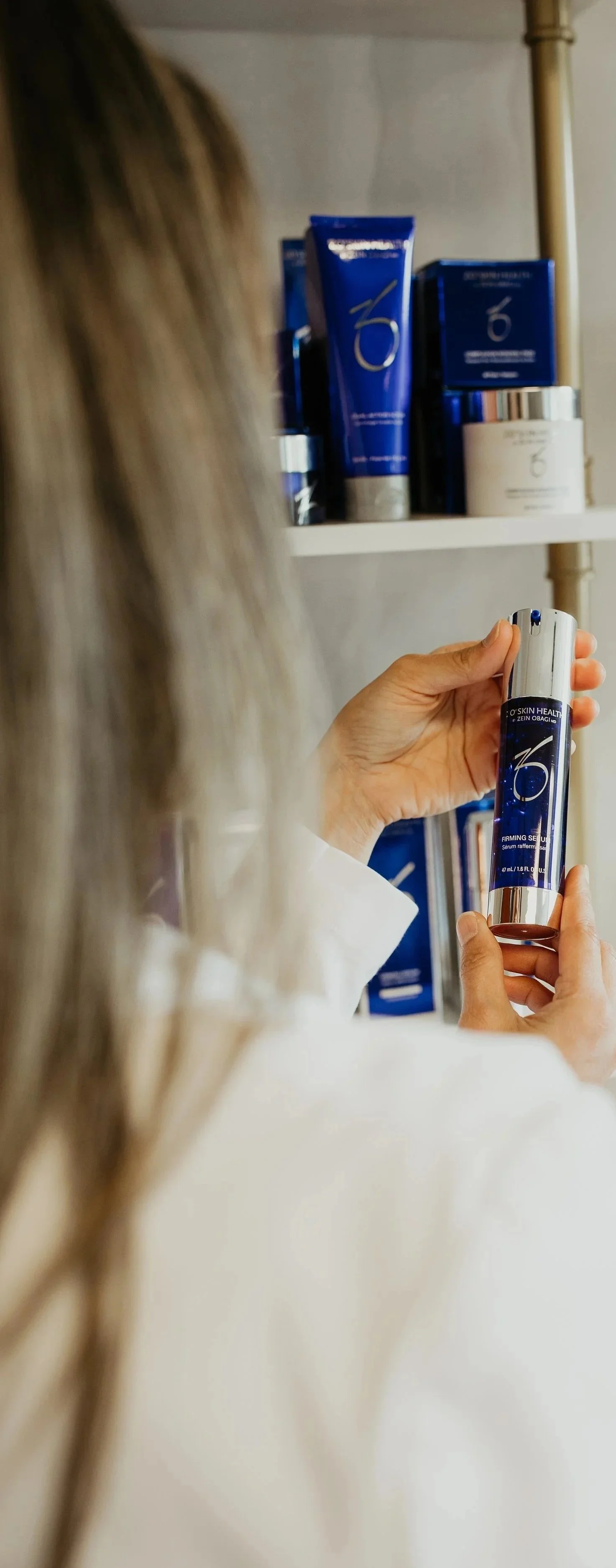 Woman browsing ZO Skin Health by Zein Obagi medical-grade skincare products on display at Sona Medical Aesthetics Newcastle WA