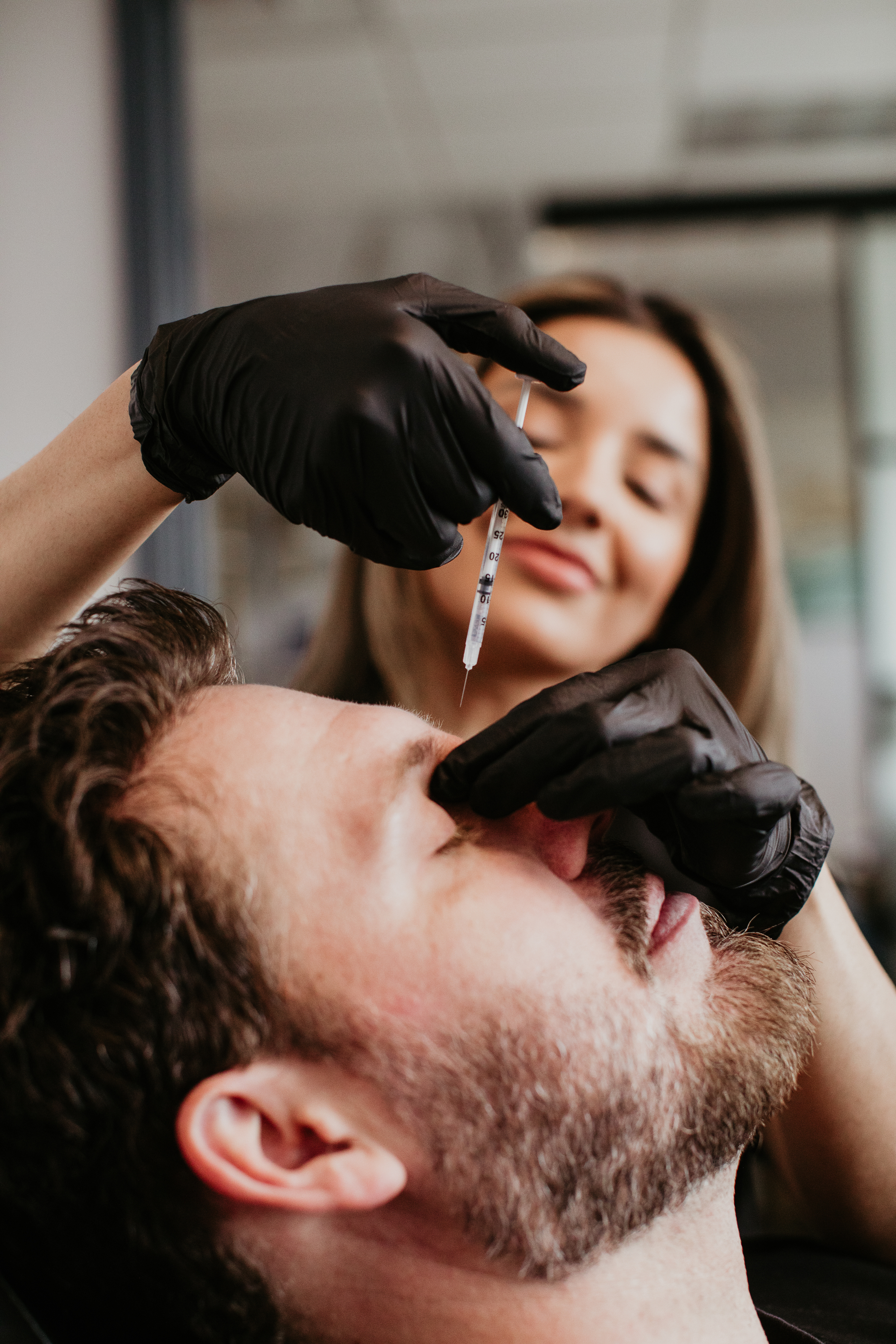 Gloved provider administering a wrinkle relaxer Botox injection to a male patient's forehead at Sona Medical Aesthetics Newcastle WA