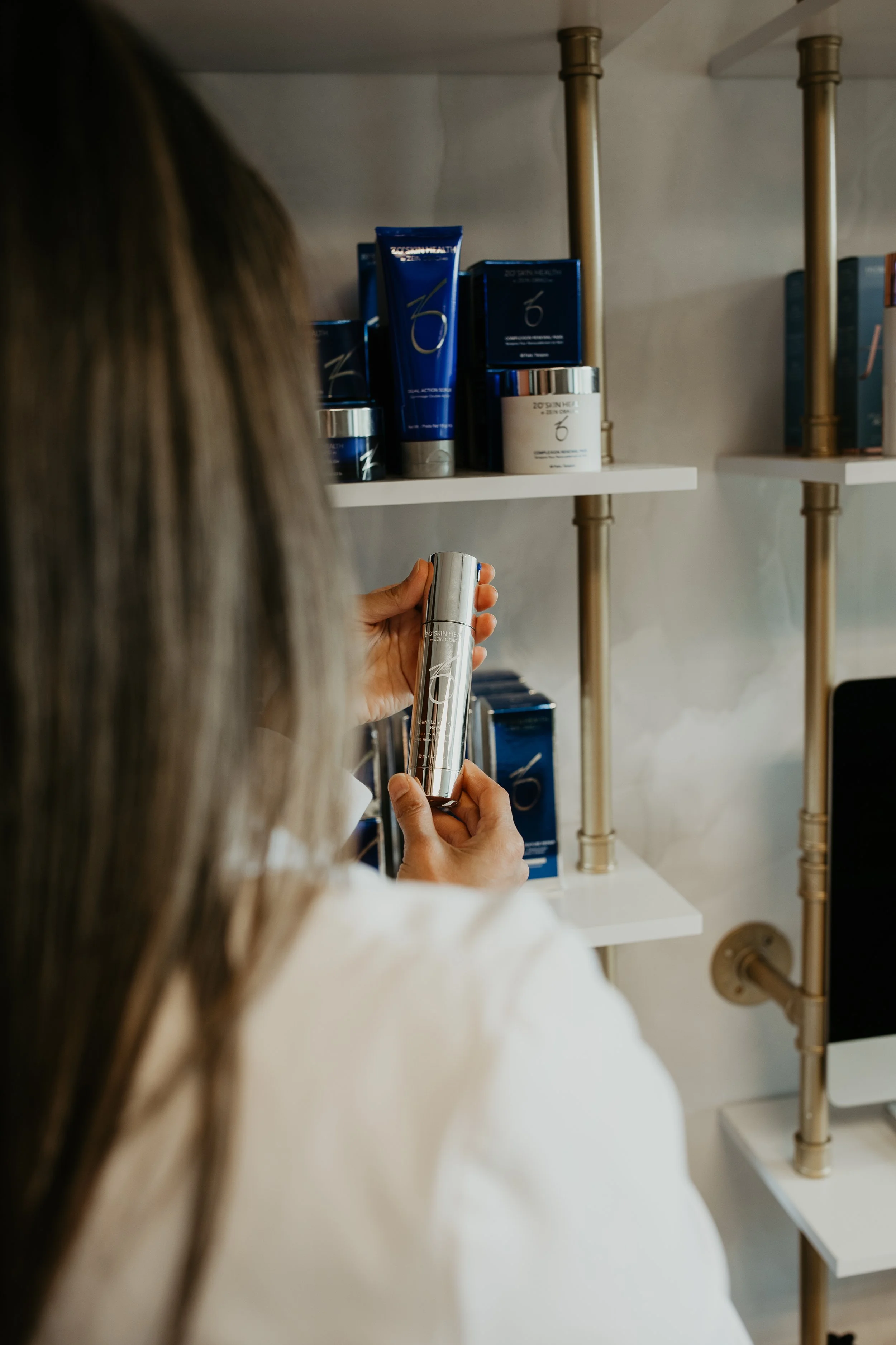 Person browsing ZO Skin Health medical-grade skincare products on display shelf at Sona Medical Aesthetics Newcastle WA