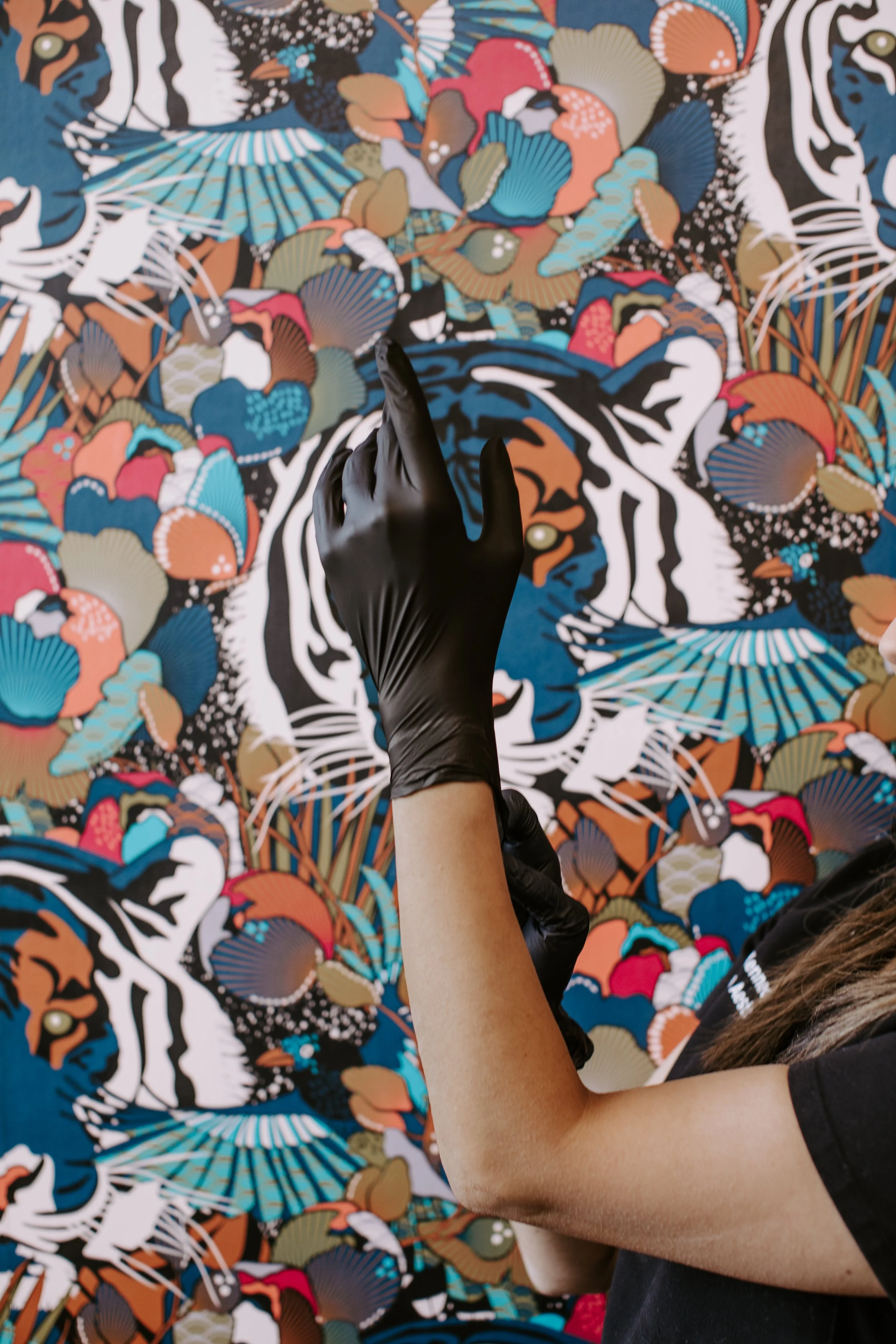 Sona Medical Aesthetics provider raising a gloved hand in front of signature tiger wallpaper before an aesthetic treatment Newcastle WA