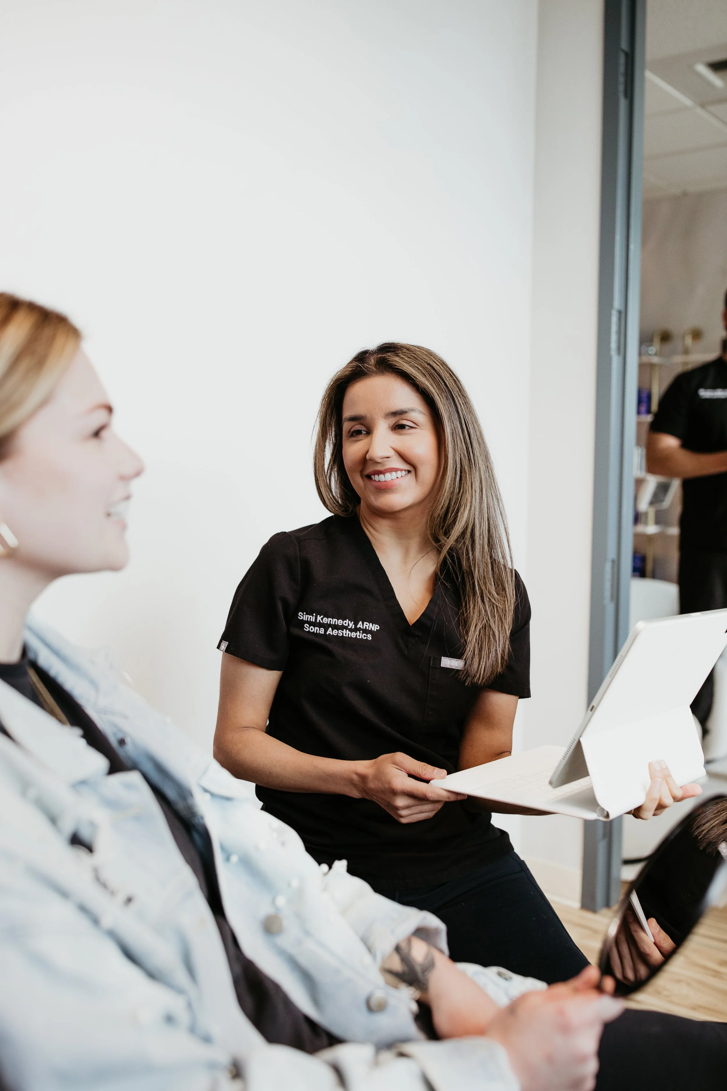   Simi Kennedy ARNP smiling while consulting with a patient about laser treatment options at Sona Medical Aesthetics Newcastle W