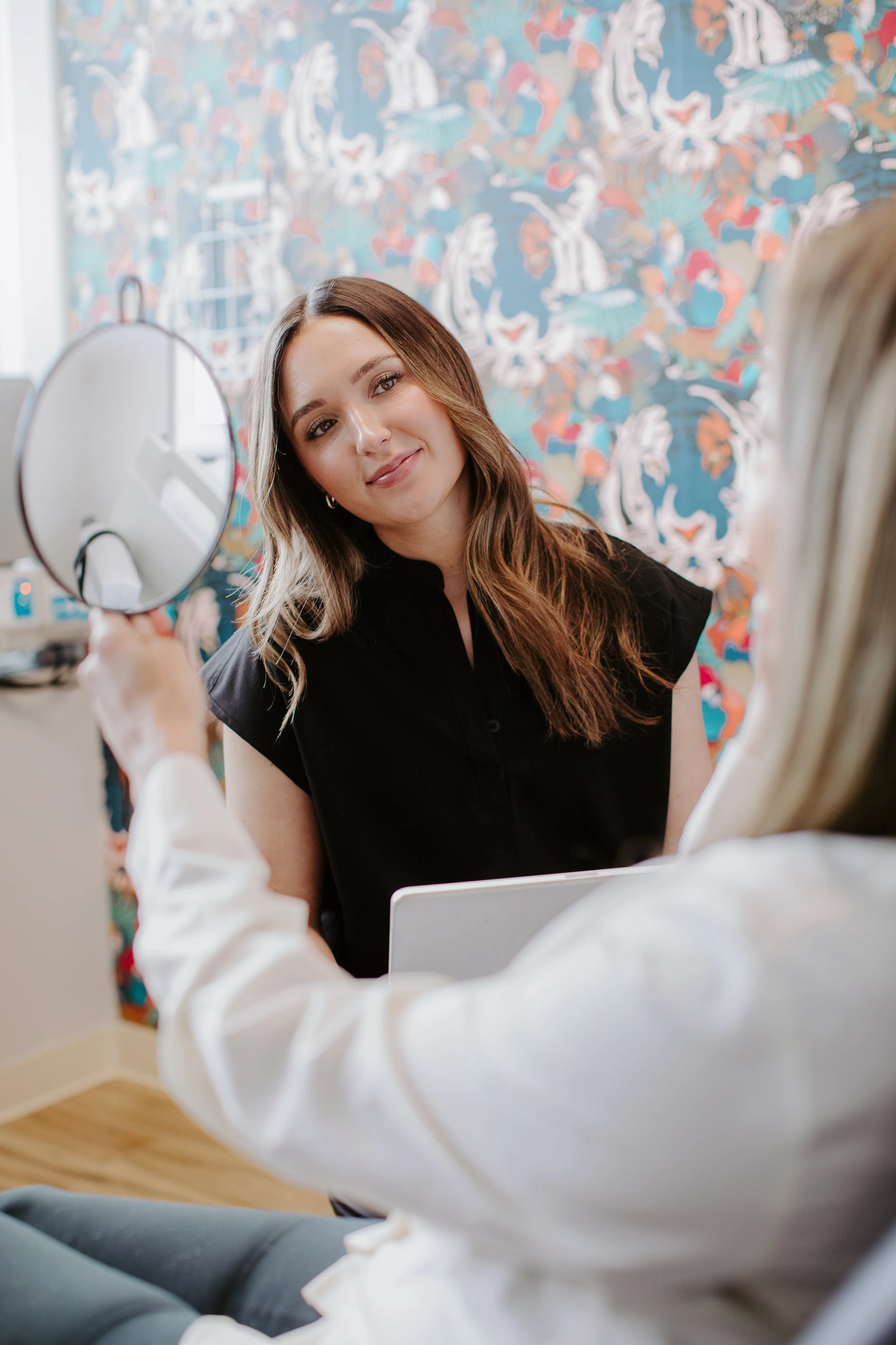 Provider holding a mirror during a consultation for acne scar treatment at Sona Medical Aesthetics Newcastle WA