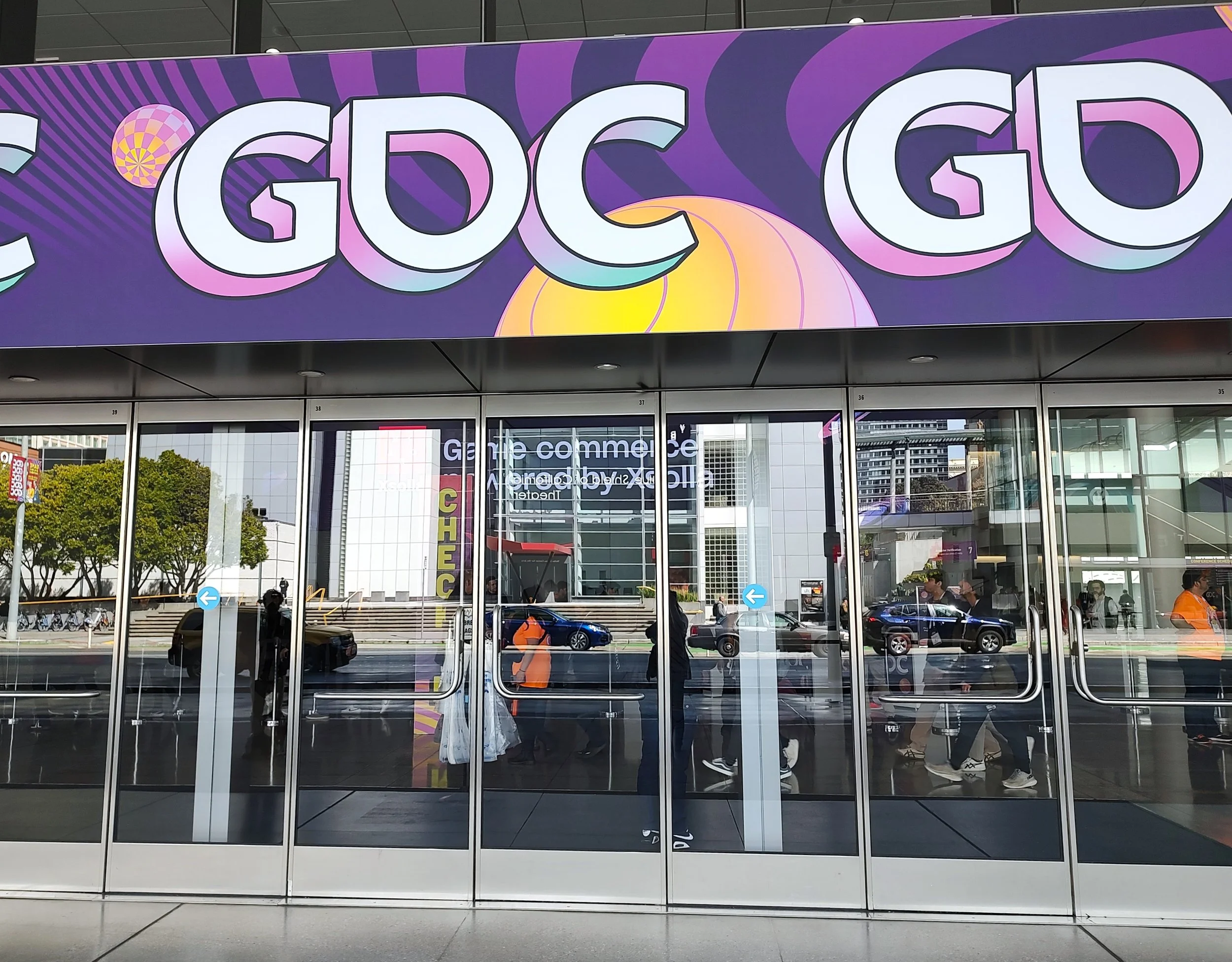 Purple sign that reads GDC above glass doors.