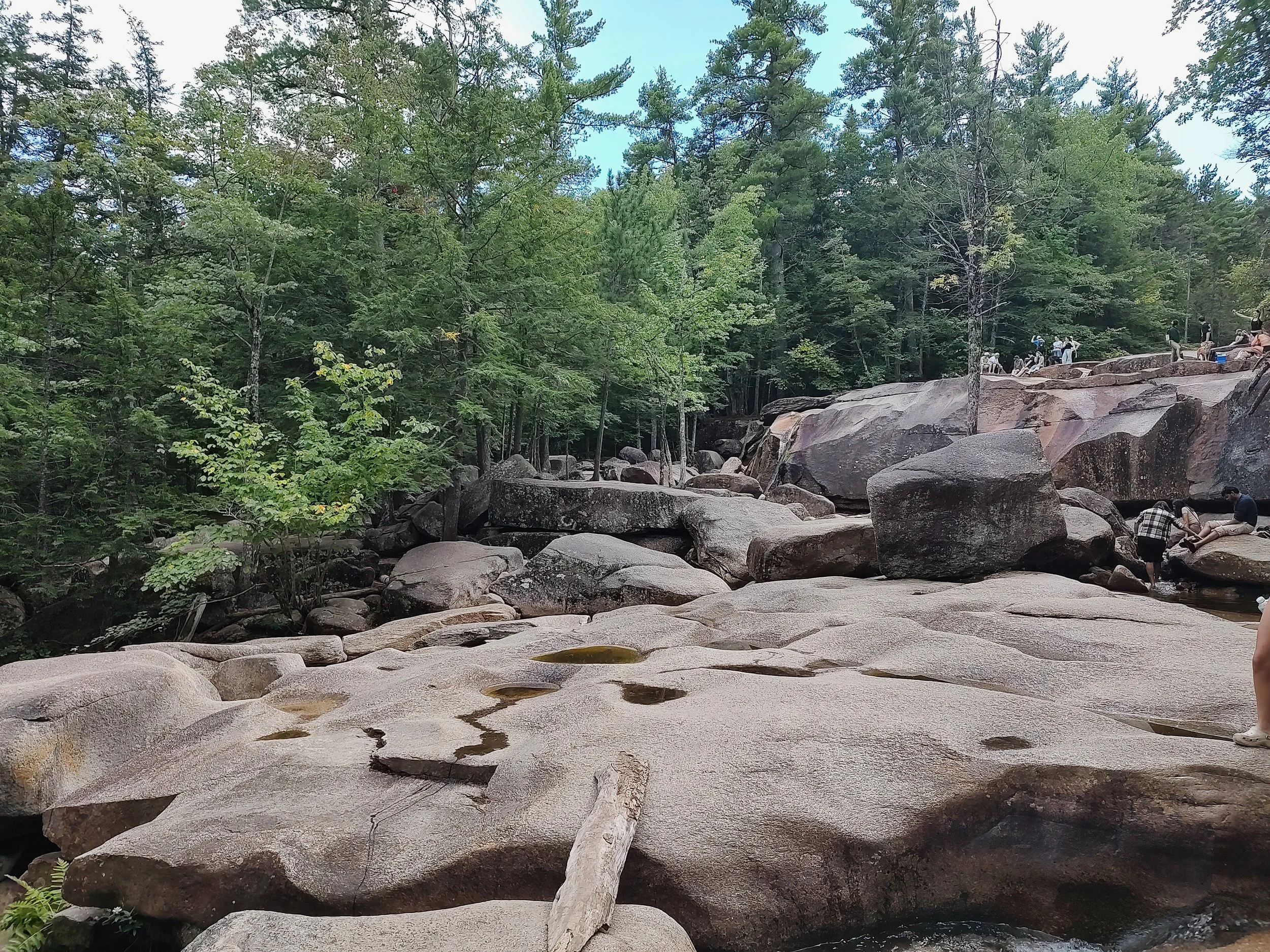 Rocks with small pools of water and people walking over them